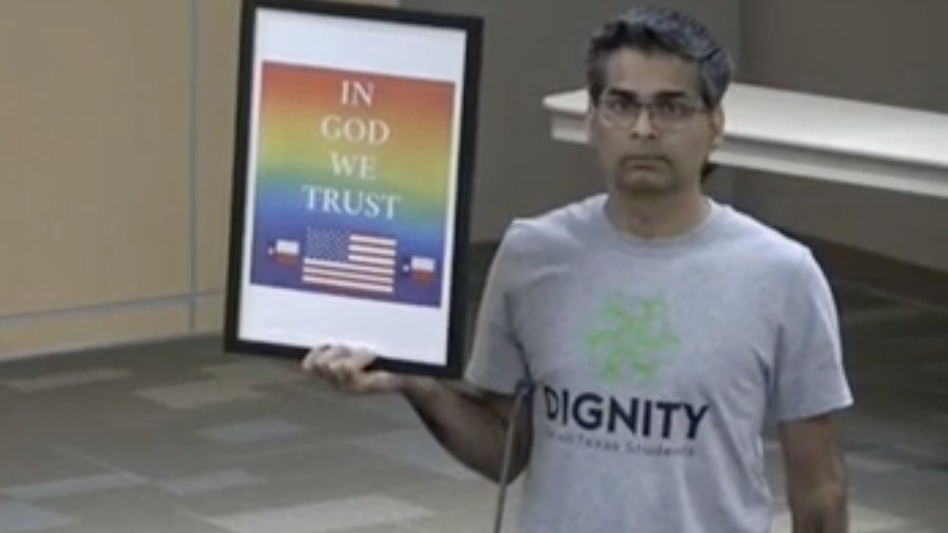 Srivan Krishna holds a rainbow-themed 'In God We Trust' sign at a board meeting of the Carroll school district in North Texas. The board declined Krishna's attempt to donate the sign.