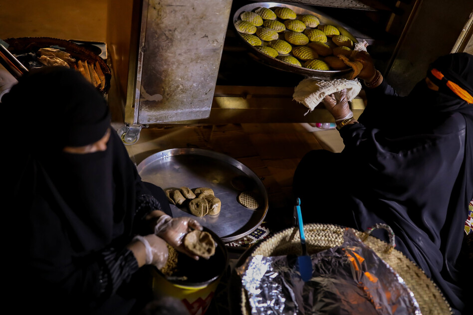Um Abdullah (right) and her granddaughter Hajer bake klaija — a waffle-like biscuit stuffed with date molasses — in Buraydah on Aug. 3, 2022. The duo are known around the city for their highly sought-after klaijas.