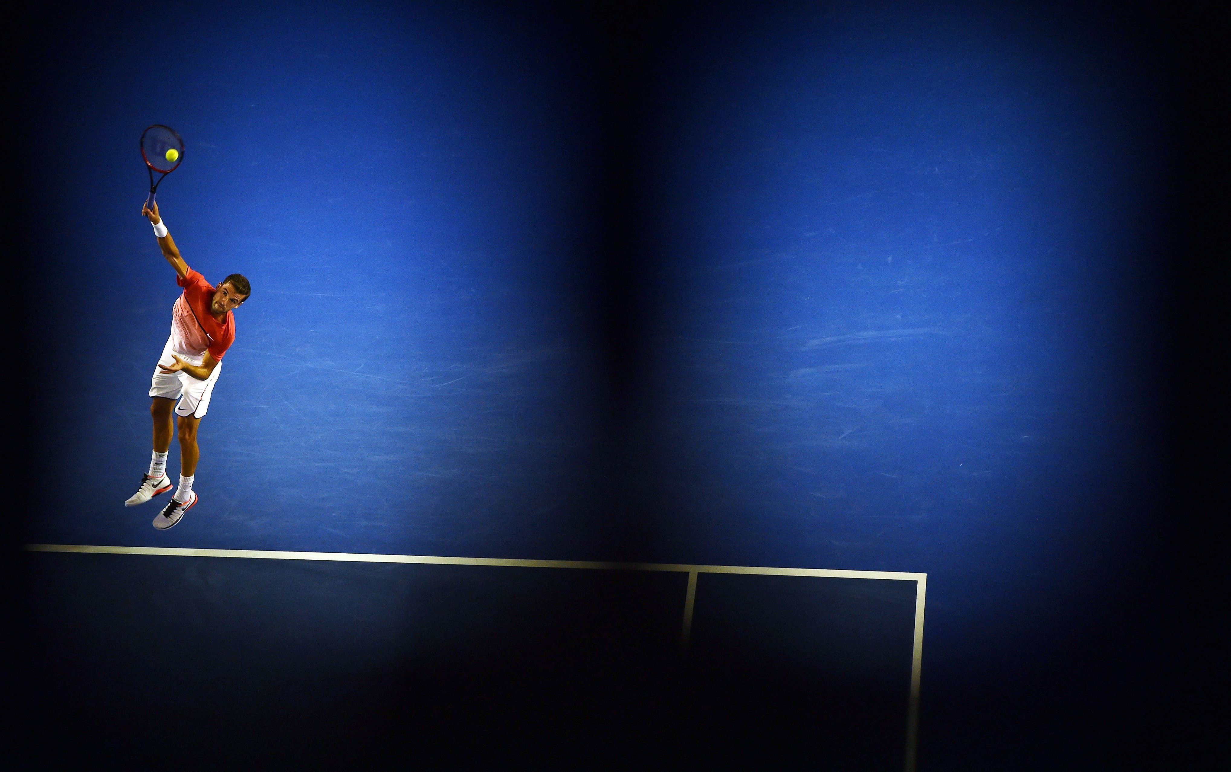 January 22, 2016: Bulgaria's Grigor Dimitrov serves against Switzerland's Roger Federer during their men's singles match on day five of the 2016 Australian Open tennis tournament in Melbourne.