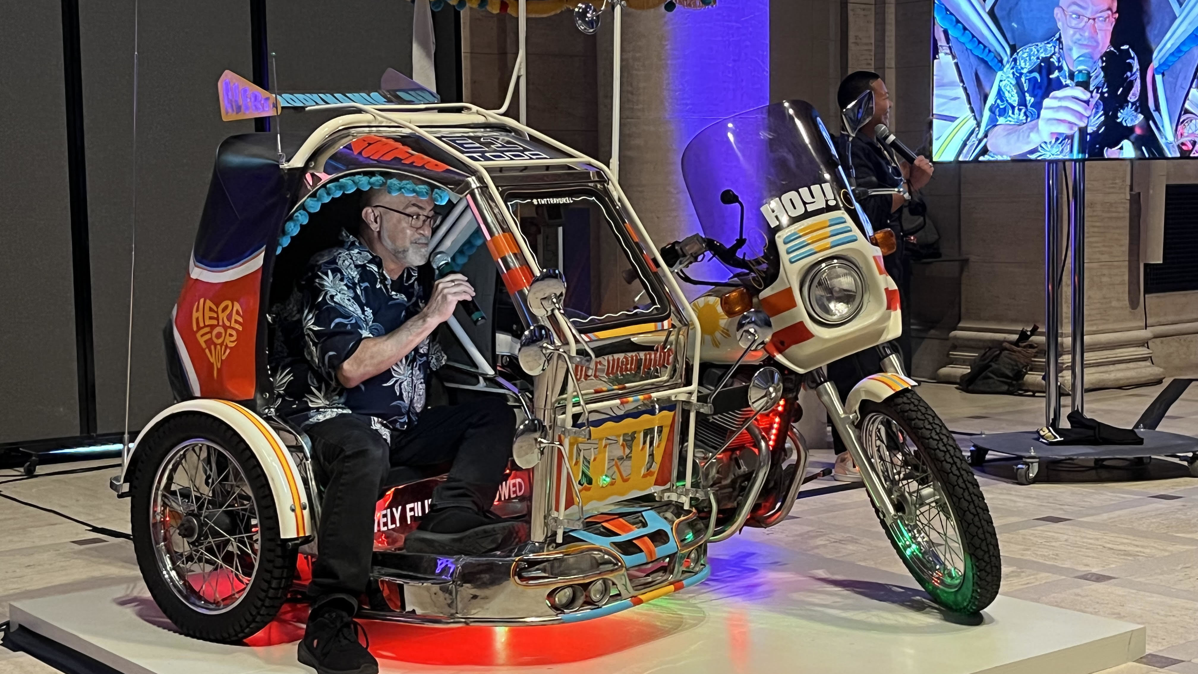 A participant sings karaoke inside "TNT Traysikel," a mobile artwork by Paolo Asuncion and Michael Arcega, two students of Carlos Villa. The piece is part of the Villa retrospective at the Asian Art Museum in San Francisco.