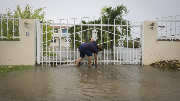 A woman clears debris on her property flooded by Hurricane Fiona in Salinas, Puerto Rico, Monday, Sept. 19, 2022.