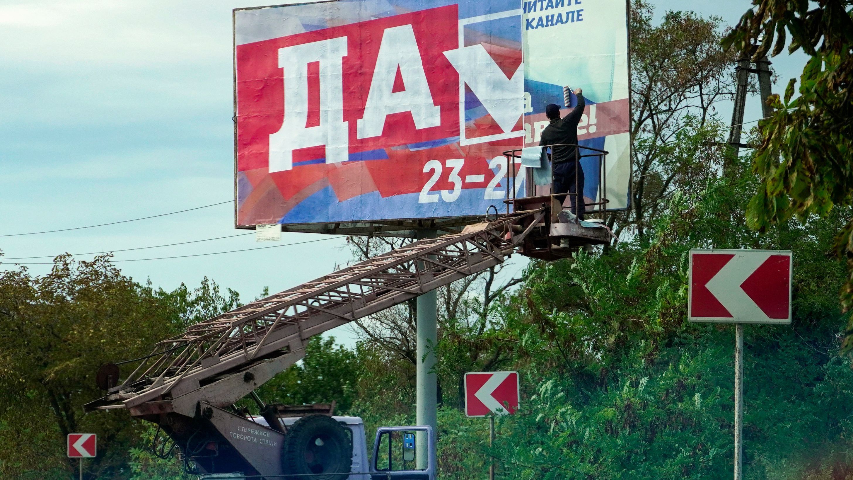 A man glues a referendum poster reading "Yes" in Berdyansk, Ukraine, on Monday.