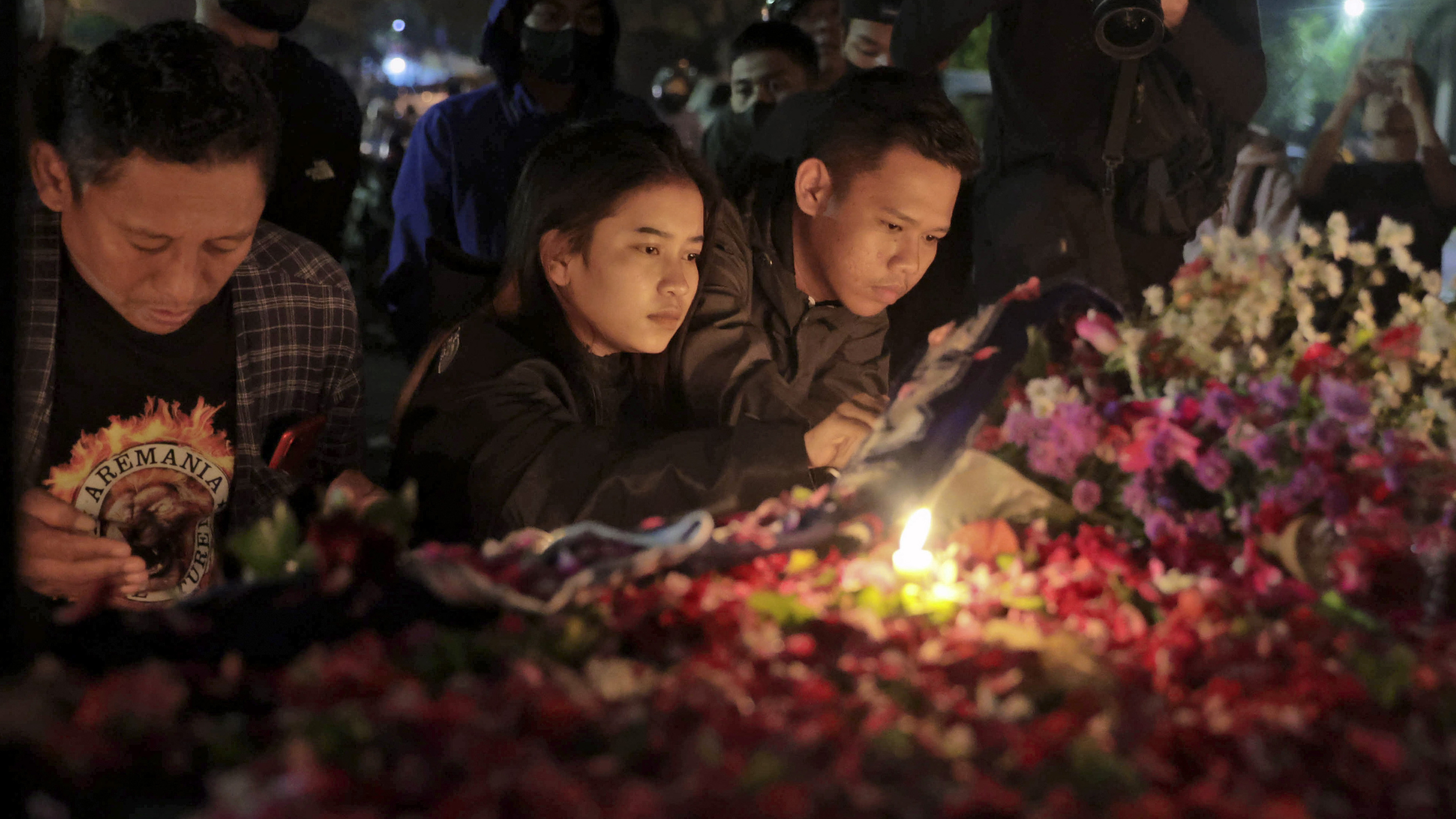 People lay flowers during a candle light vigil for the victims of Saturday
