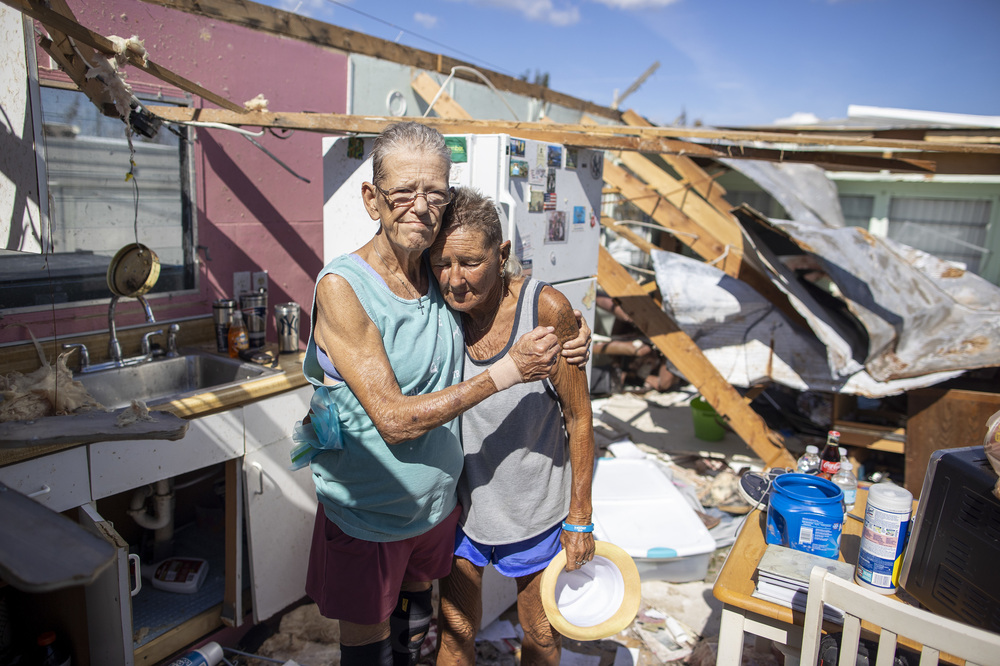 Debbie Lewis and Diana Bisson, partners of 43 years, stand in the kitchen of what remains of their home in the Flamingo Bay neighborhood on Pine Island, Fla., on Monday. They are planning to leave the island as soon as the road out is passable. (Carlos Osorio for NPR)