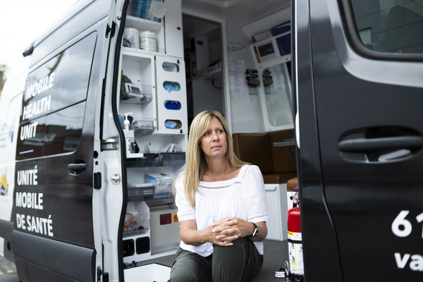 Donna Sarrazin, the managing partner at Recovery Care, sits in the doorway of the clinic's mobile health unit.