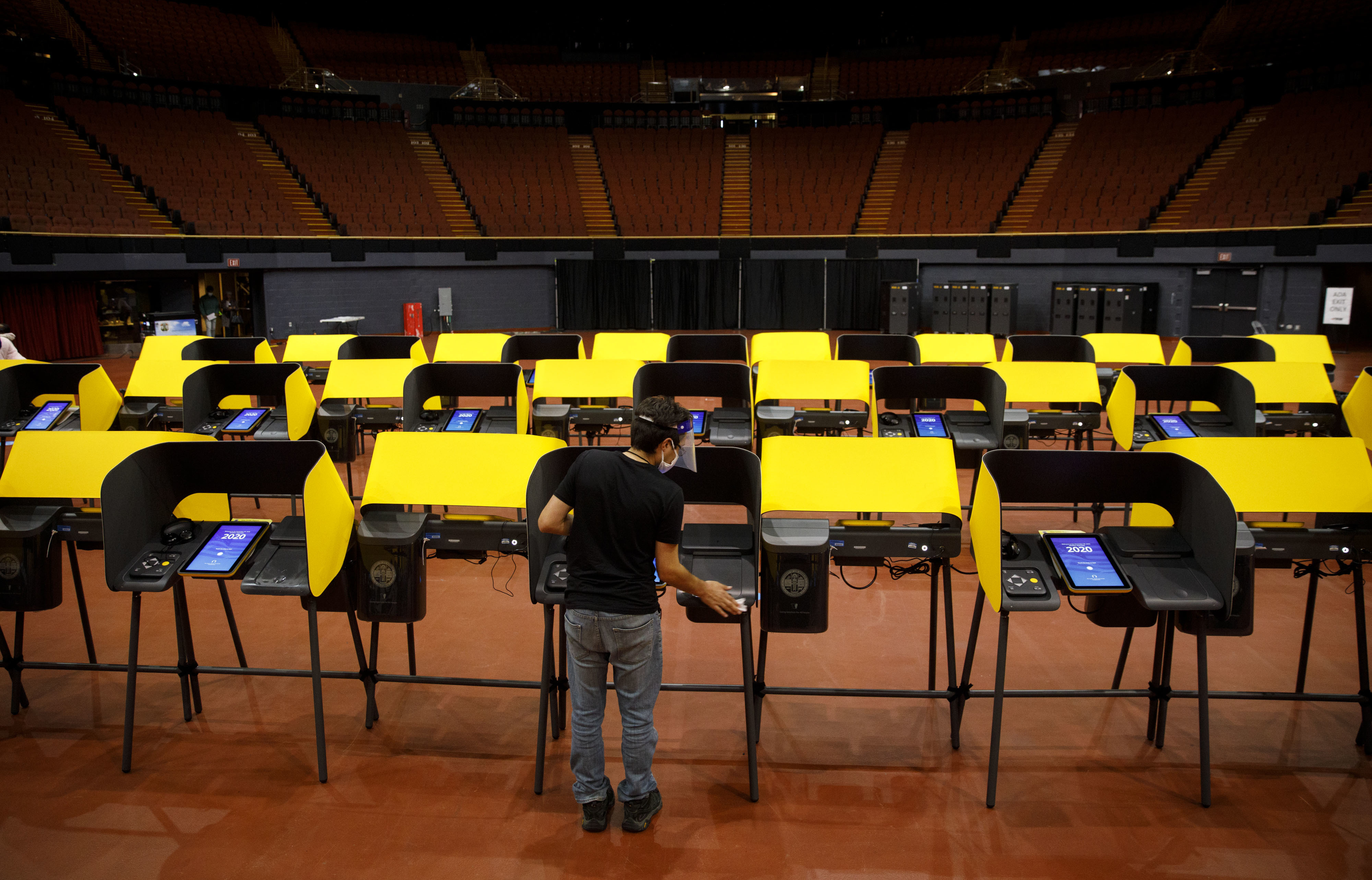 A poll worker sanitizes ballot marking machines at an early voting location in Inglewood, Calif., on Oct. 29, 2020. The Los Angeles County district attorney alleges that the CEO of Konnech, which makes scheduling software for poll workers, improperly gave Chinese contractors access to sensitive employee data. (Bloomberg via Getty Images)