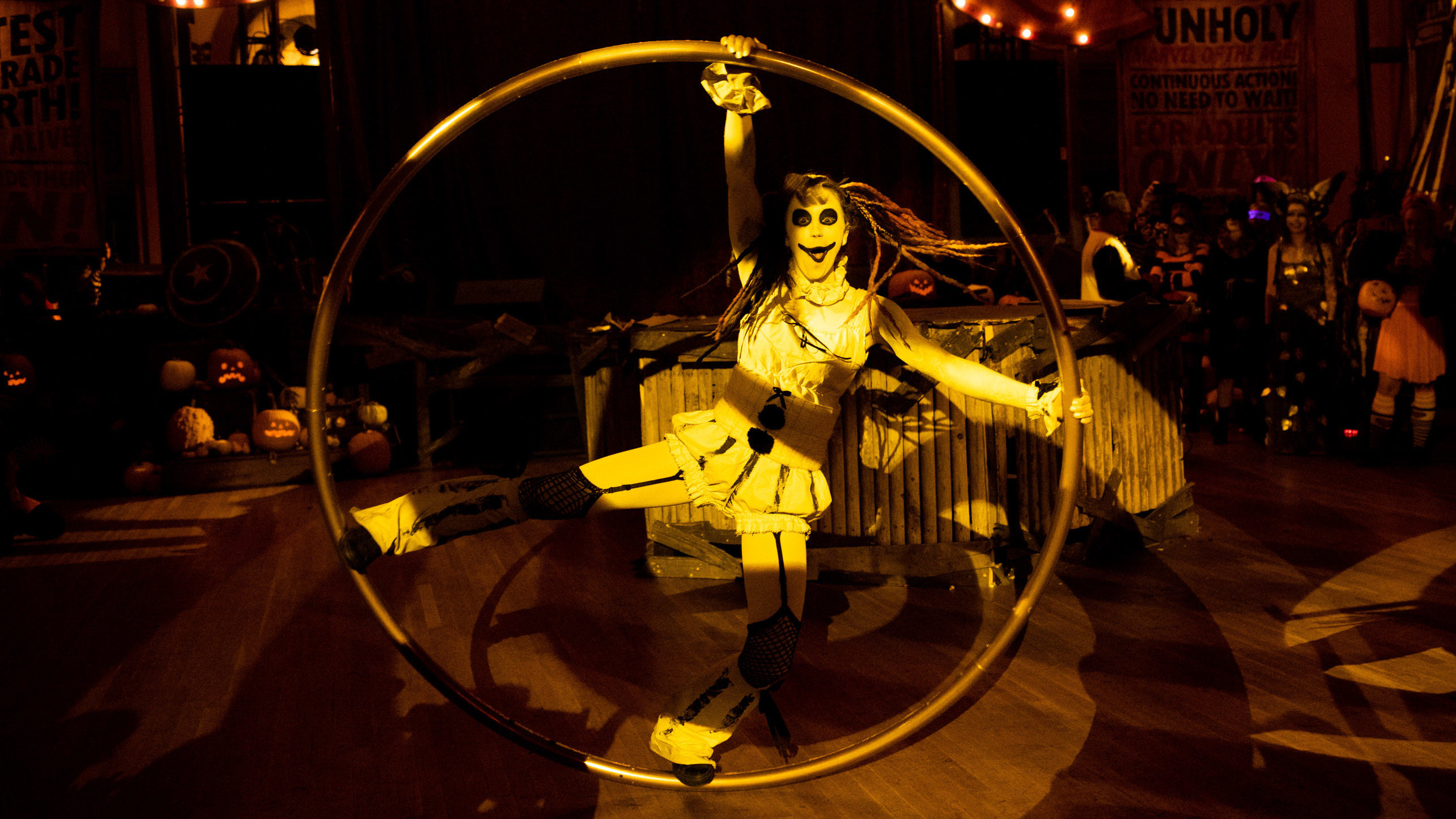 A performer swings around on a giant hula hoop as people cheer.