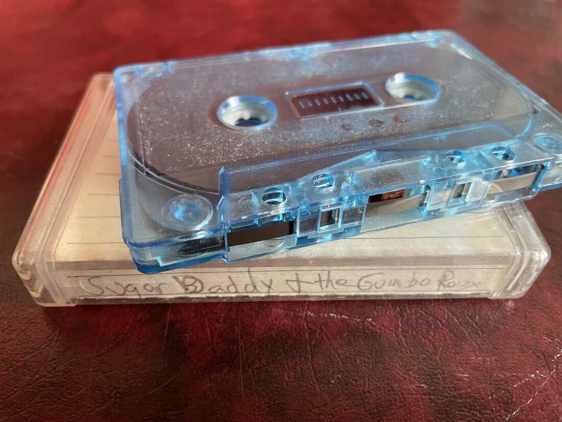 The cassette is placed on top of the box and it says "Sugar Daddy and Gumbo."