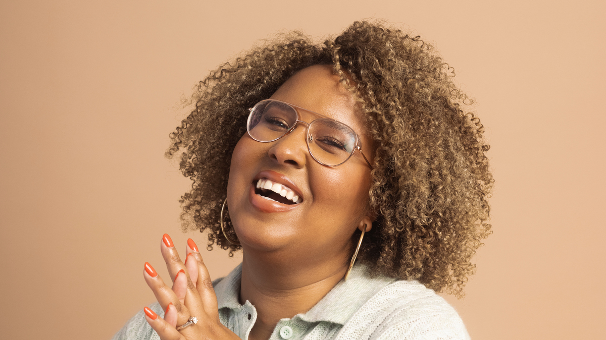 Portrait of Brittany Luse, the new voice of NPR's It's Been A Minute. Brittany is in front of an orange-brown background.