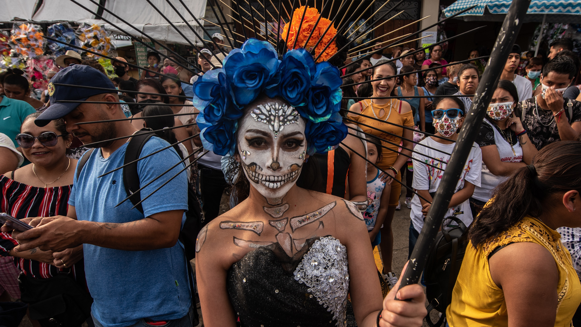 A young woman dressed in Santa Muerte makeup waits outside the pantheon with other participants.