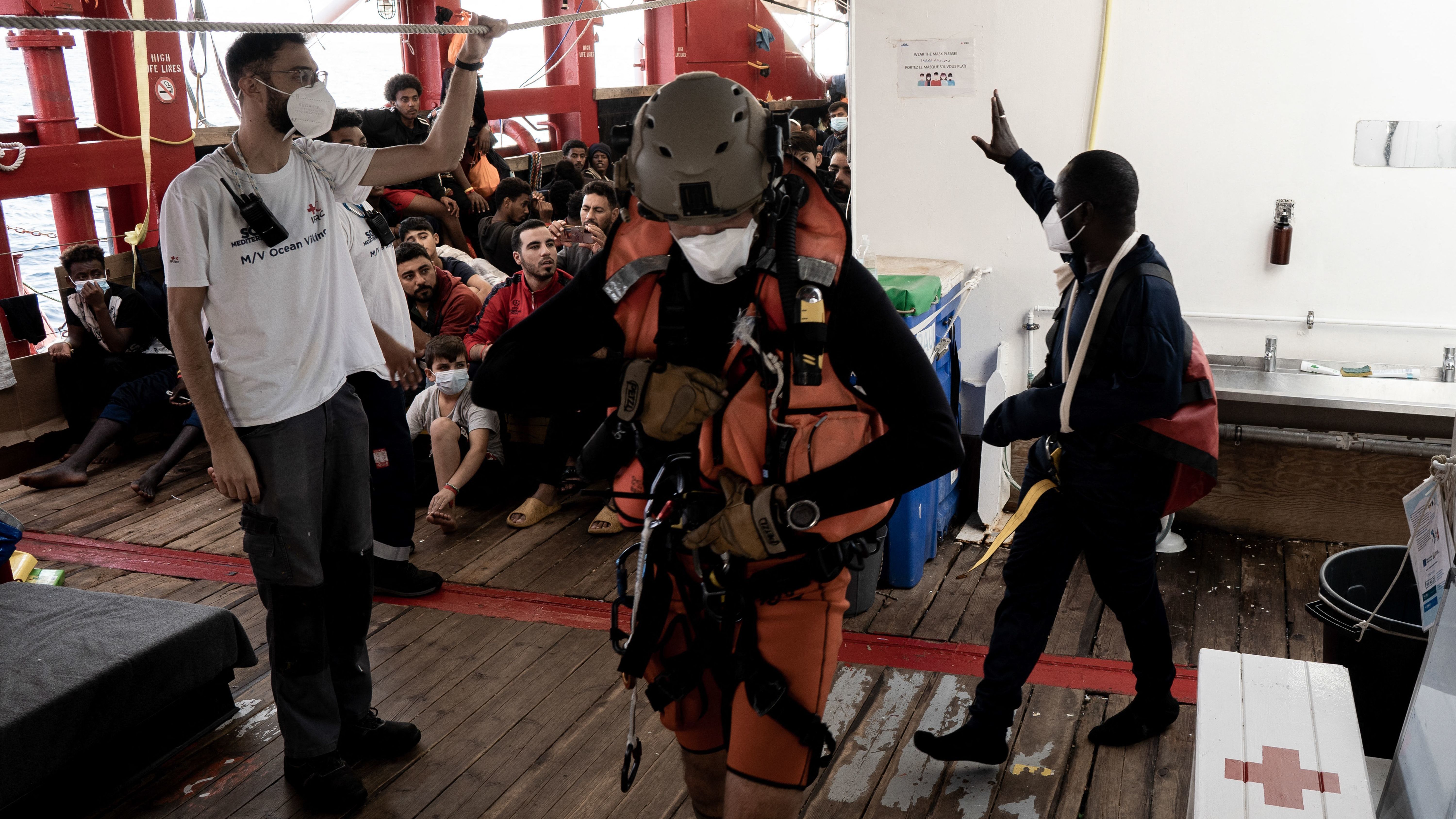 A man with an arm injury and in need of urgent medical care, right, waves to fellow migrants before he is flown by helicopter by the French Army from the Ocean Viking rescue ship on Thursday. French authorities evacuated several migrants from the ship ahead of the ship docking in Toulon on Friday.