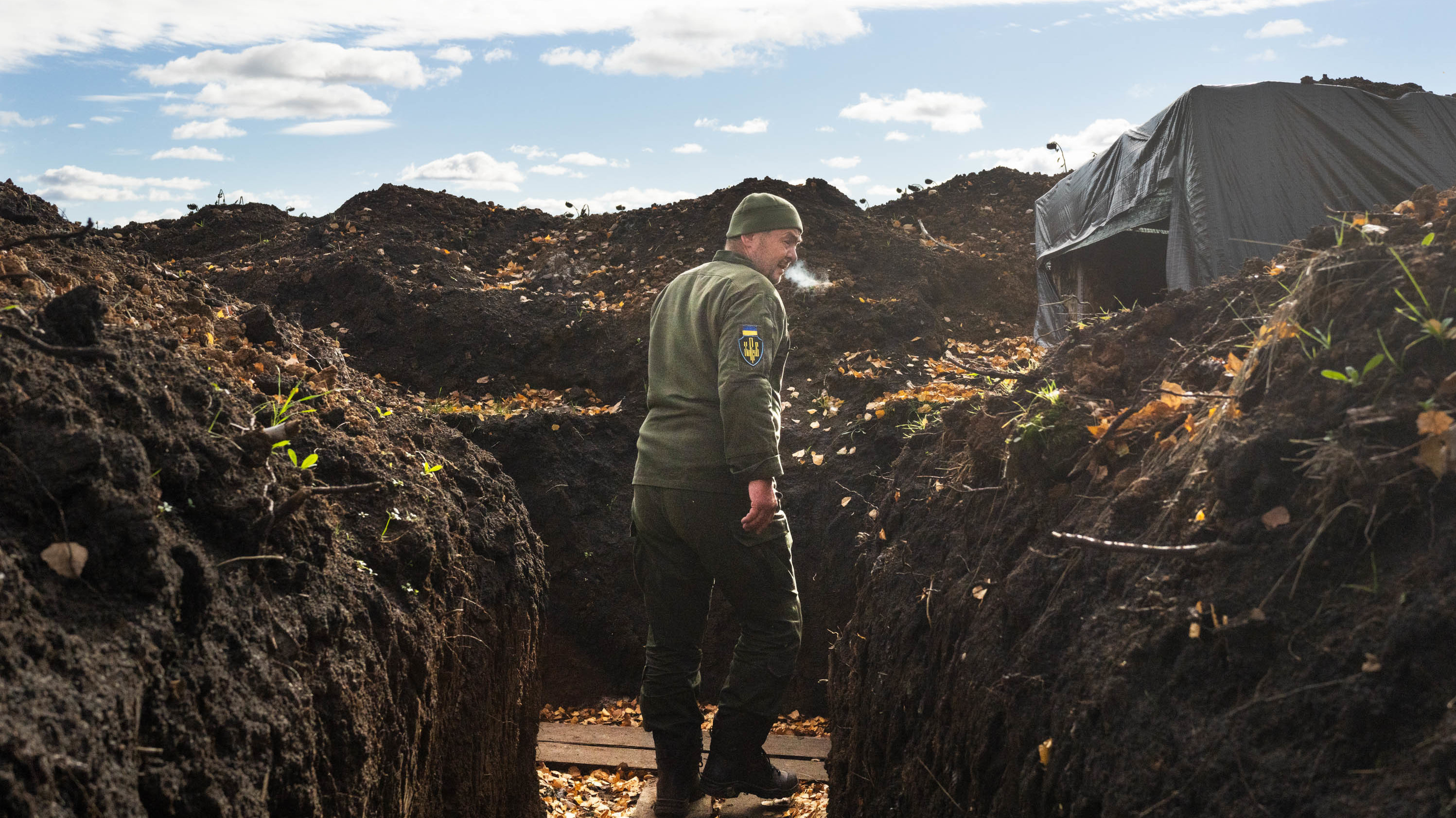 A soldier in Kharkiv region walks through a trench, his breath showing in the cold air. (NPR)