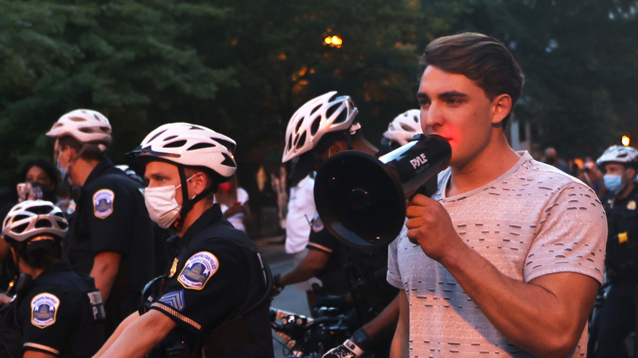 Jacob Wohl, pictured here surrounded by police officers at a 2020 protest in Washington D.C., is one of two right-wing activists who were behind a 2020 robocall scheme that targeted minority voters. Wohl will now face probation, fines and 500 hours of voter registration assistance for pleading guilty to telecommunications fraud.