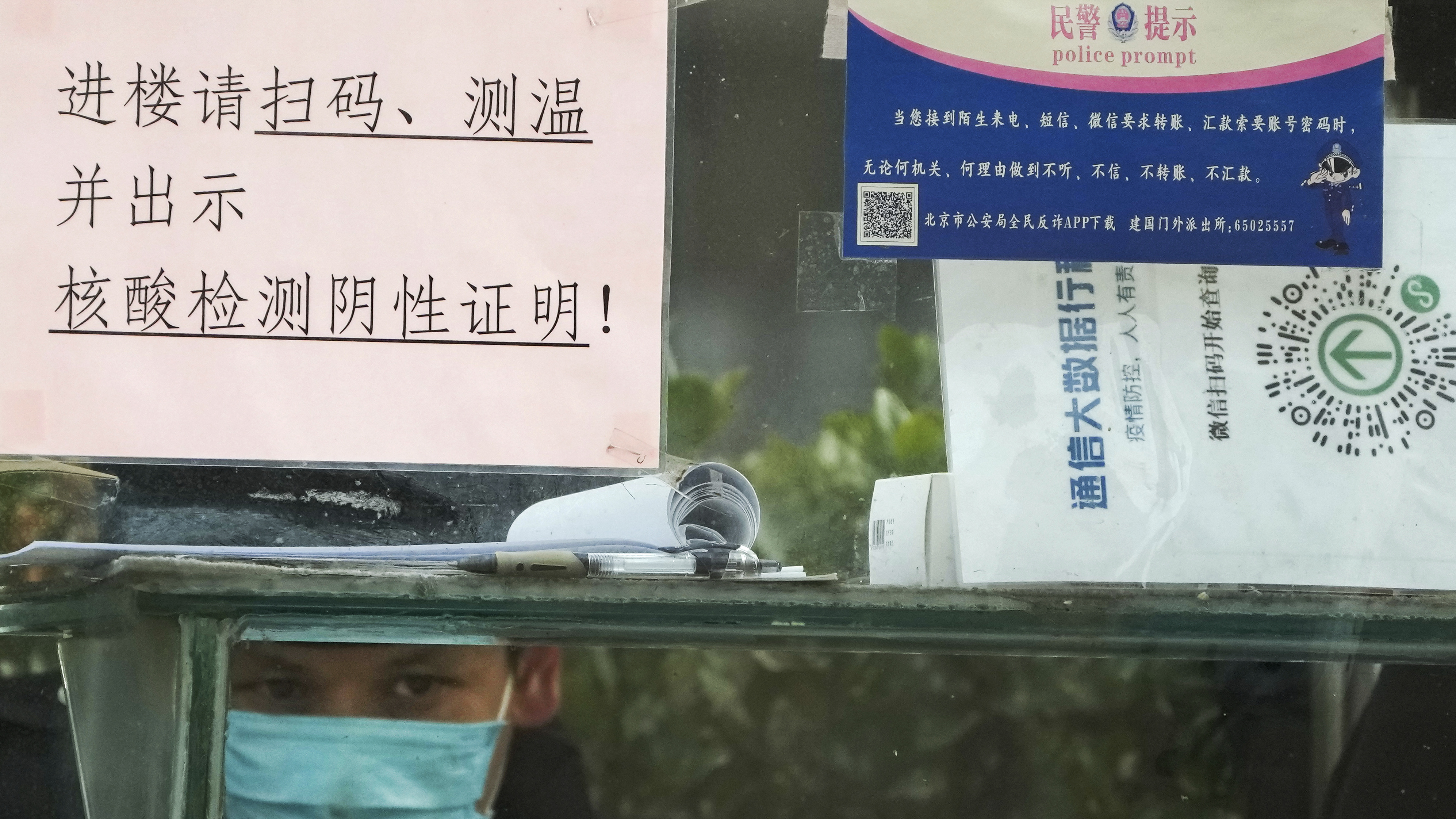 A security guard keeps watch inside a booth outside an office building in Beijing, Monday, Dec. 12, 2022.