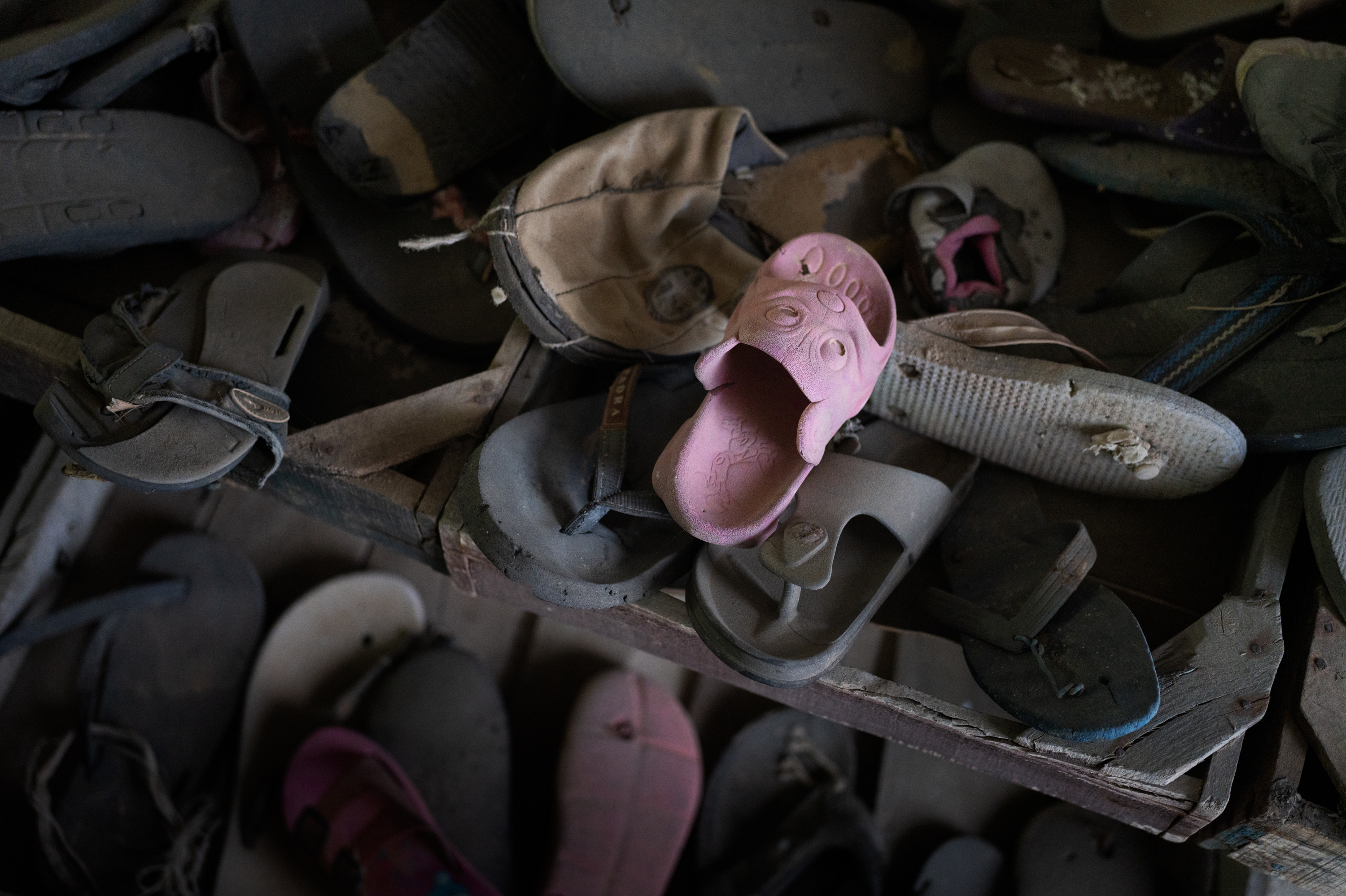 A small pink slipper sits atop a pile of shoes collected from the shores of the Mediterranean in Zarzis, Tunisia. The museum housing the shoes honors the migrants who die crossing the sea. (NPR)