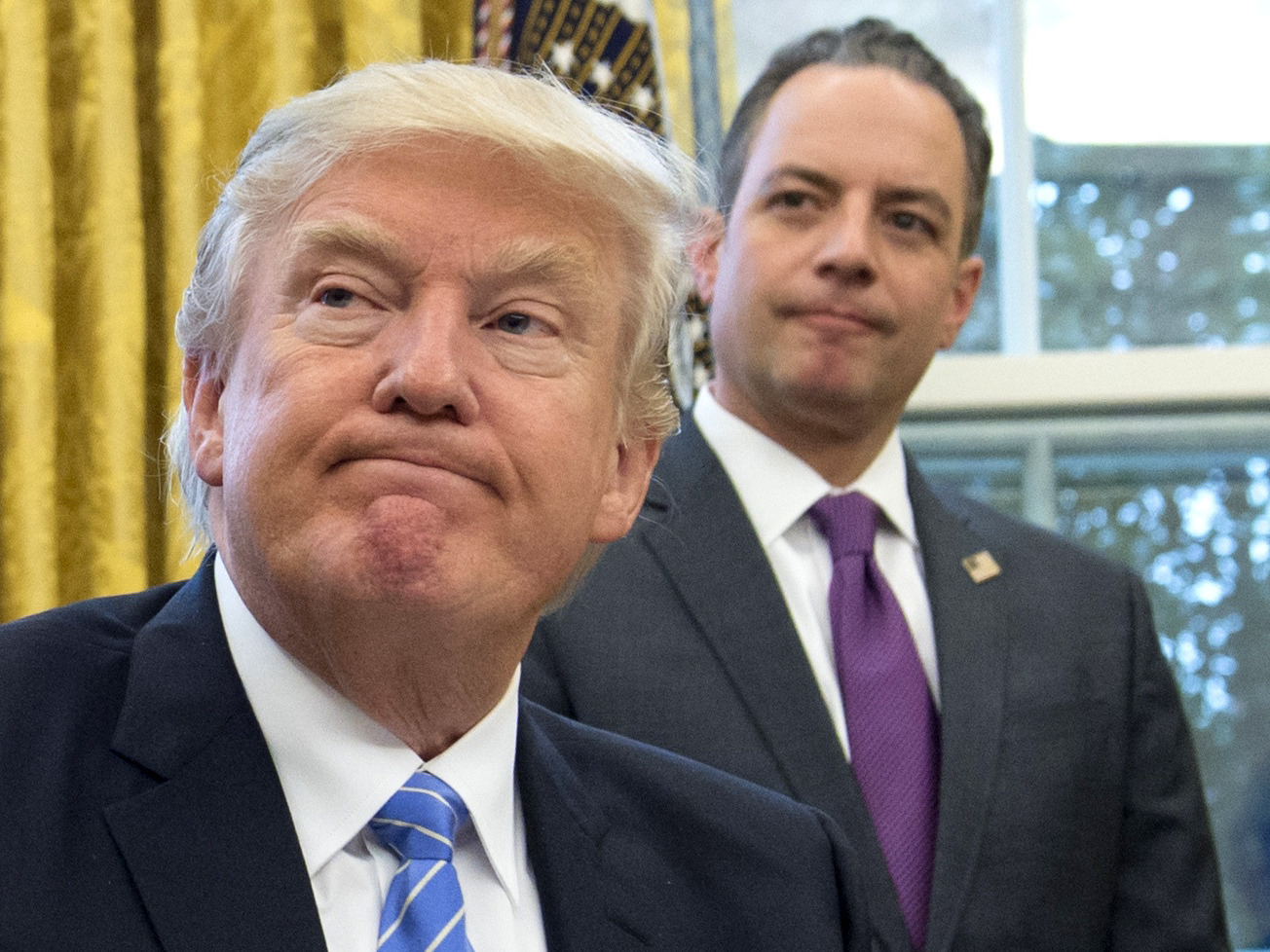 US President Donald Trump signs an executive order as Chief of Staff Reince Priebus looks on in the Oval Office of the White House in Washington, DC, January 23, 2017. (AFP via Getty Images)