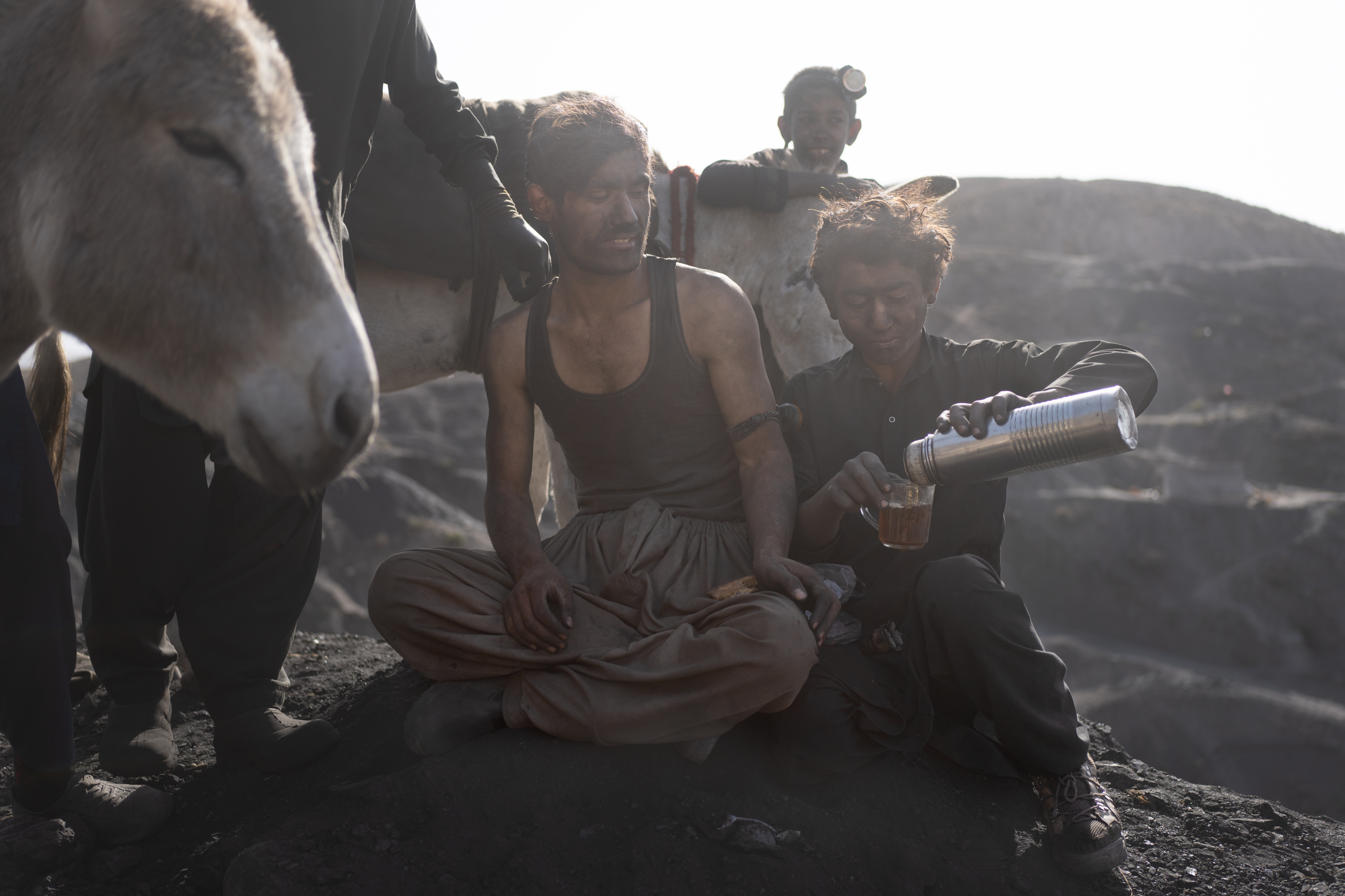 In Afghanistan, coal mining relies on the labor of children 2 Miners take a break with their donkeys and drink tea near the end of a shift.