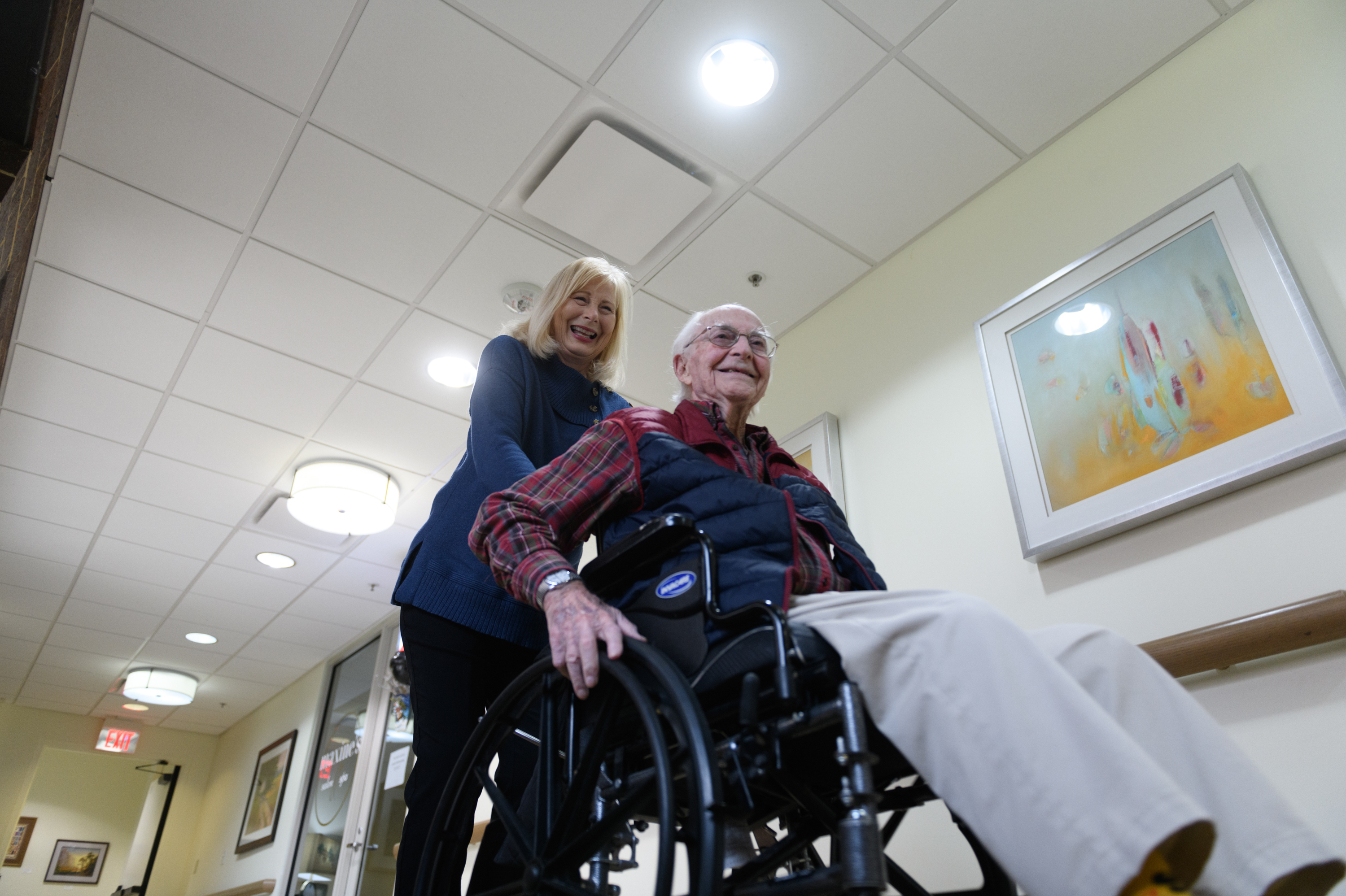 Paula Naylor pushes her father, Paul Romanello, with his wheelchair on Dec. 21 in Tulsa, Okla. Romanello was recently celebrated by the Centenarians of Oklahoma when he turned 100 years old. (Michael Noble Jr. for NPR)