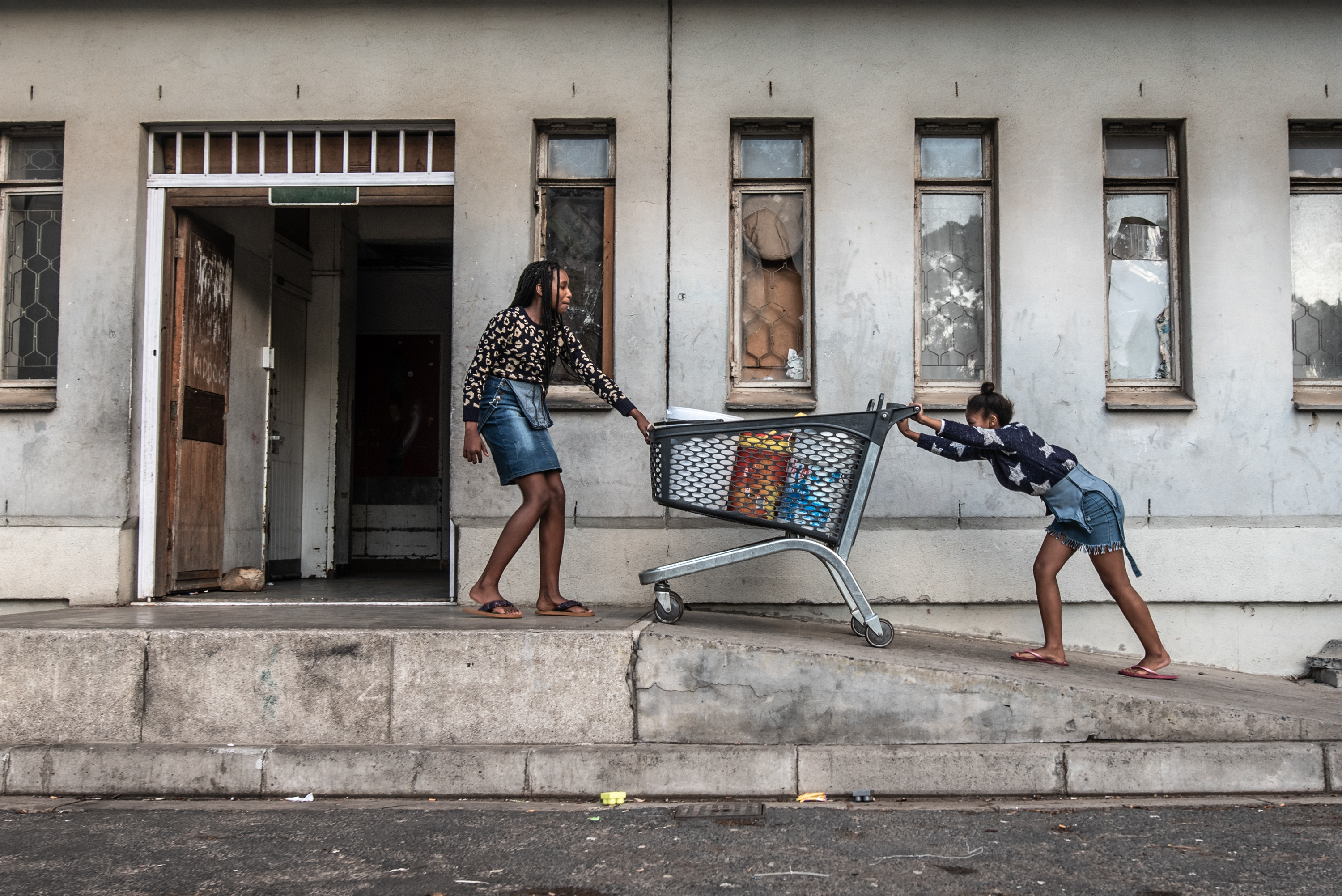 Inside South Africa's 'hijacked' buildings: 'All we want is a place to call home' 13 Two girls push a shopping cart full of buckets of water to their families' rooms in Ahmed Kathrada House.