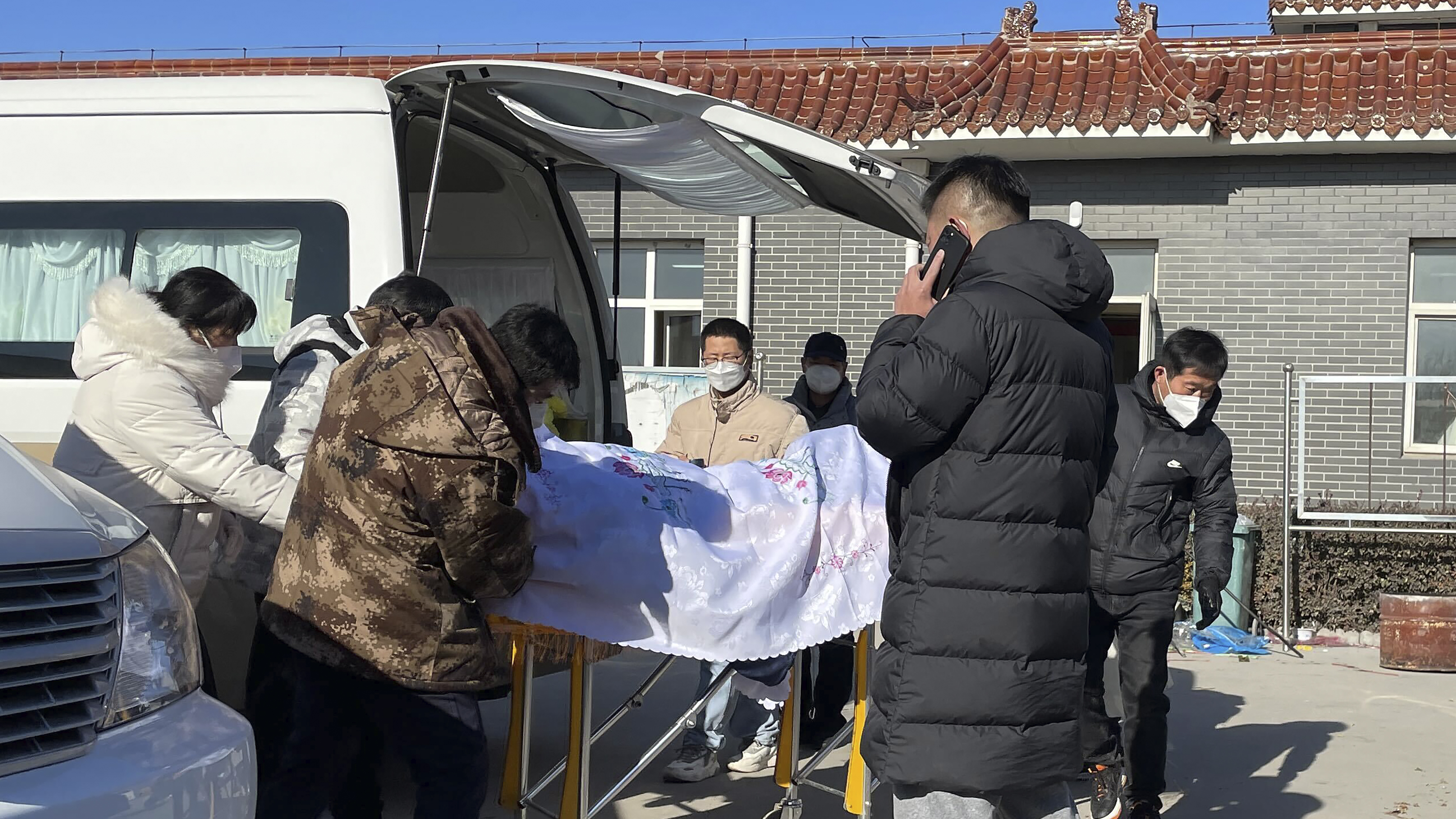 Liang from Beijing, center, looks on as his 82-year-old grandmother is brought in a casket to the Gaobeidian Funeral Home in northern China