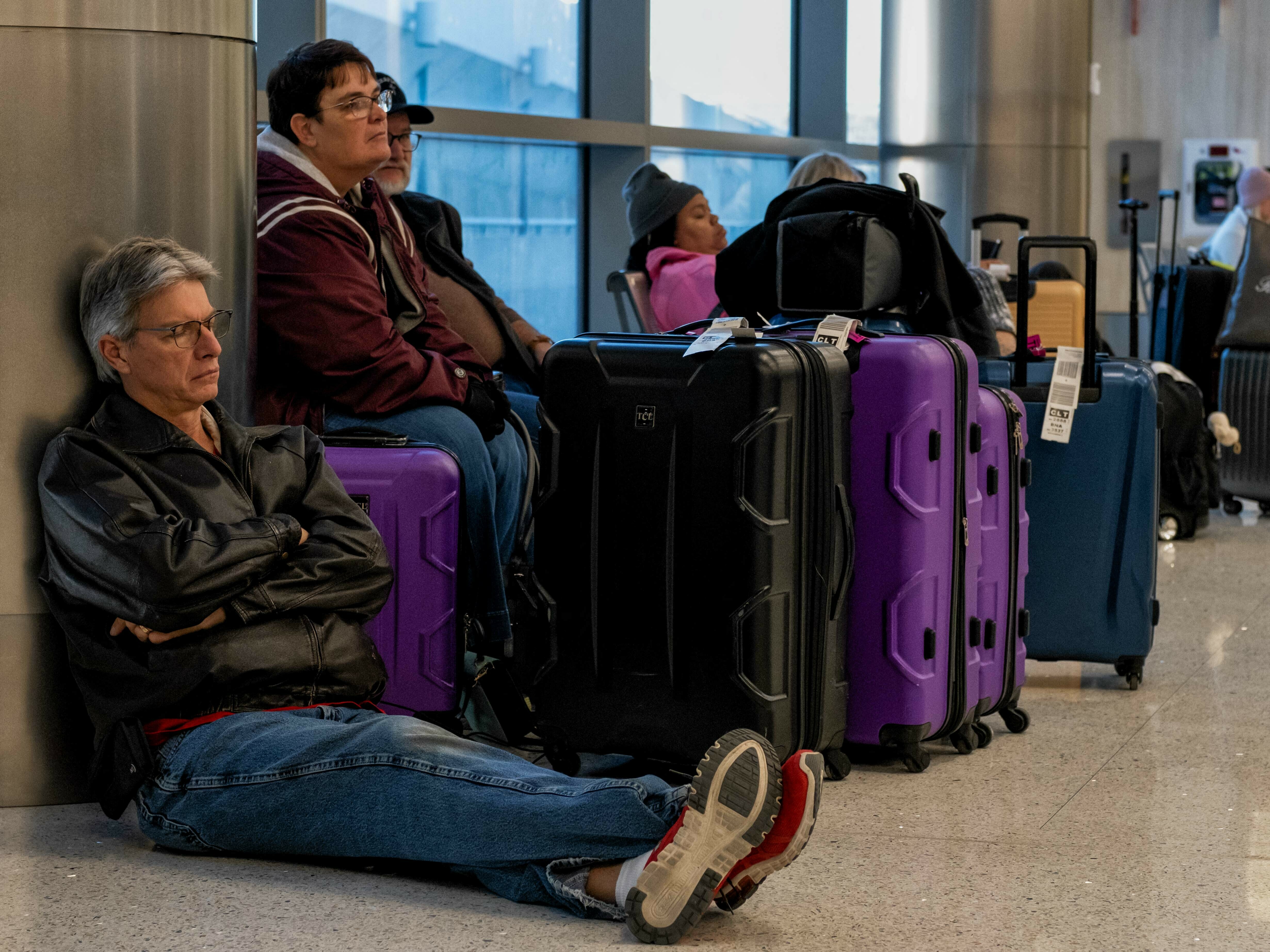 Travelers wait next to their luggage near the Southwest Airlines baggage claim area at the Nashville International Airport after the airline canceled thousands of flights in Nashville, Tenn., on Tuesday. (AFP via Getty Images)