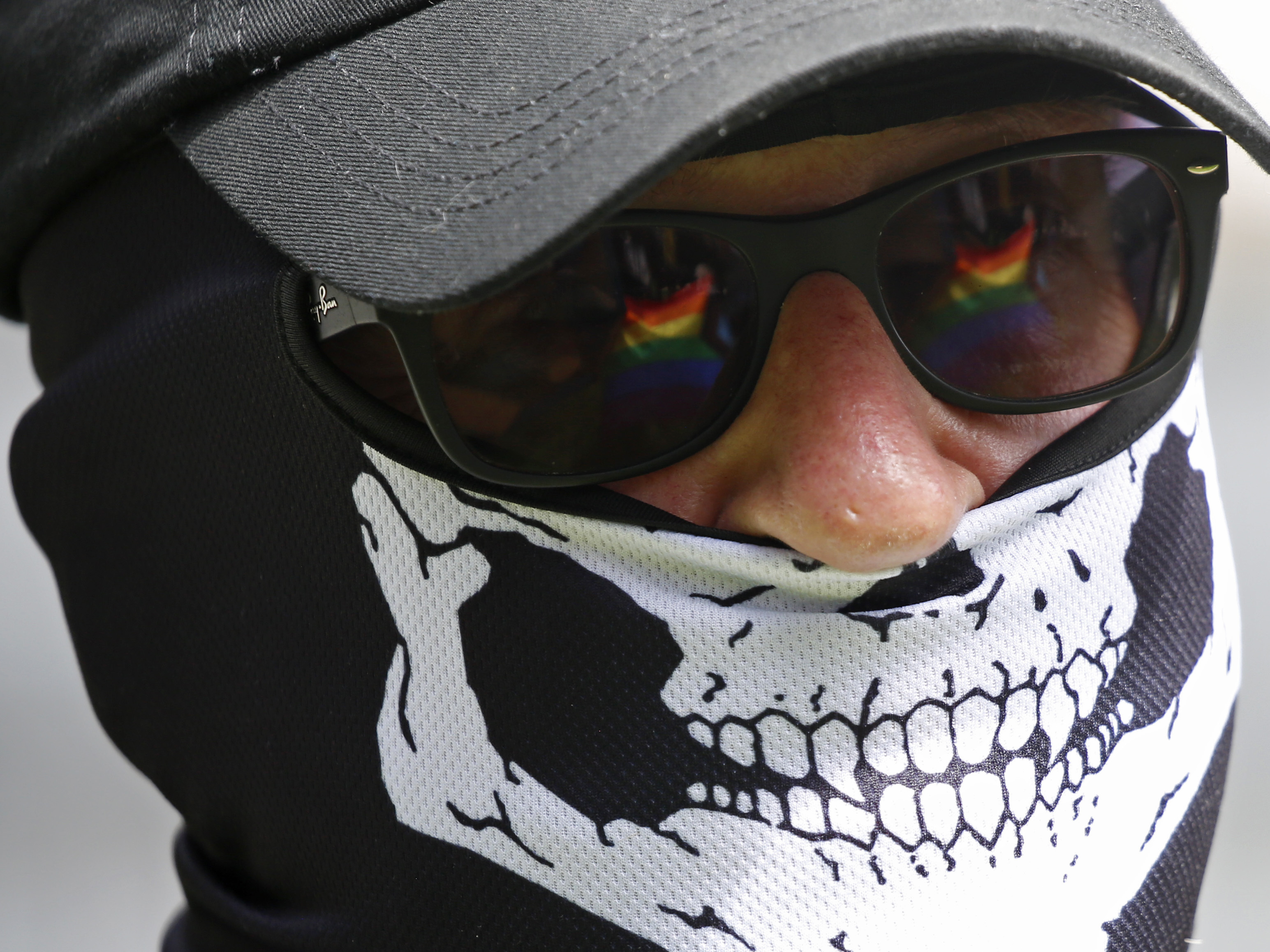 The Pride flag is reflected in the glasses of a white nationalist who came to protest at the LGBTQ+ community's "Pride in the Park" event in Coeur d'Alene, Idaho, on June 11, 2022.