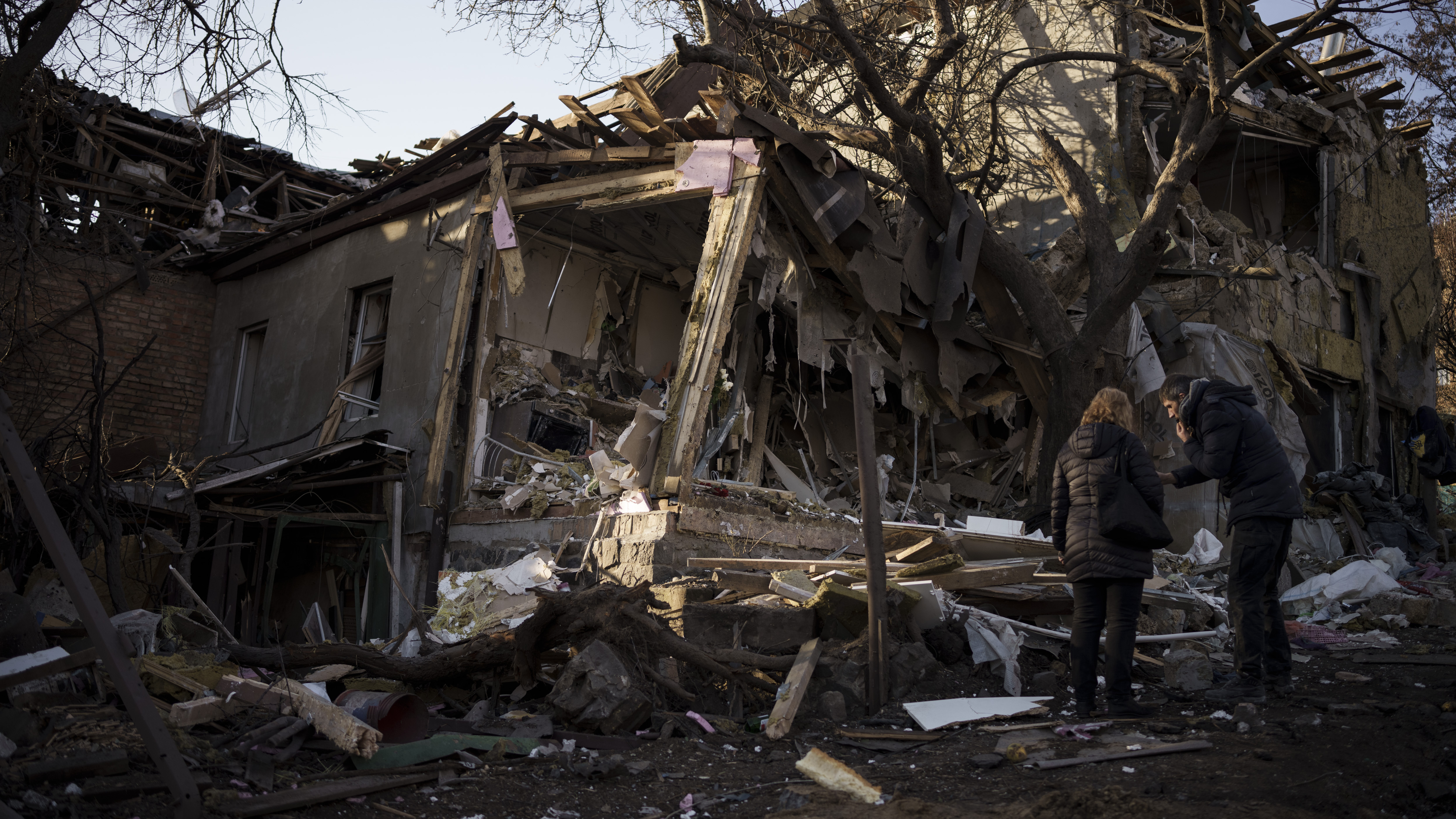 Serhii Kaharlytskyi, right, stands outside his home, destroyed after a Russian attack in Kyiv, Ukraine, Monday, Jan. 2, 2023. Kaharlytskyi