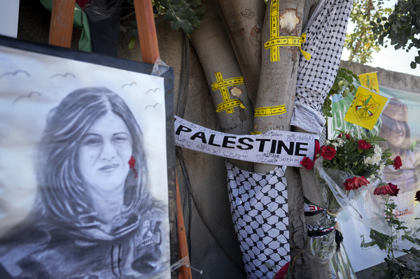 Yellow tape marks bullet holes on a tree and a portrait and flowers create a makeshift memorial, at the site where Palestinian-American Al-Jazeera journalist Shireen Abu Akleh was shot and killed in the West Bank city of Jenin, May 19, 2022.