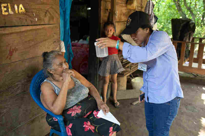 Neudy Rojop (right) shows Eduviges Lopez the mosquitoes trapped in her home by the insectazooka in Los Encuentros, Guatemala.