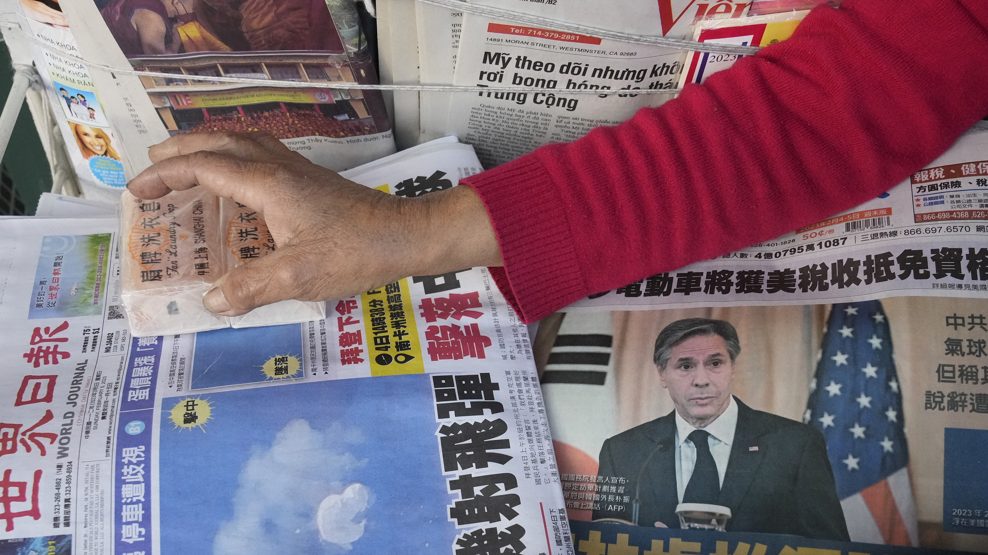 Business owner "Annie" weights down copies of the Chinese Daily News newspaper showcasing pictures of a suspected Chinese spy balloon, in the Chinatown district of Los Angeles Sunday, Feb. 5, 2023.