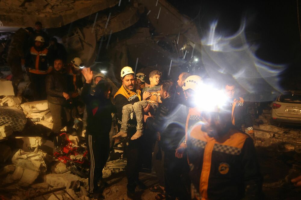 Rescue workers carry a boy they recovered from the rubbles of a building after an earthquake in Dana, a town in rebel-held Idlib, early Monday morning. (AFP via Getty Images)