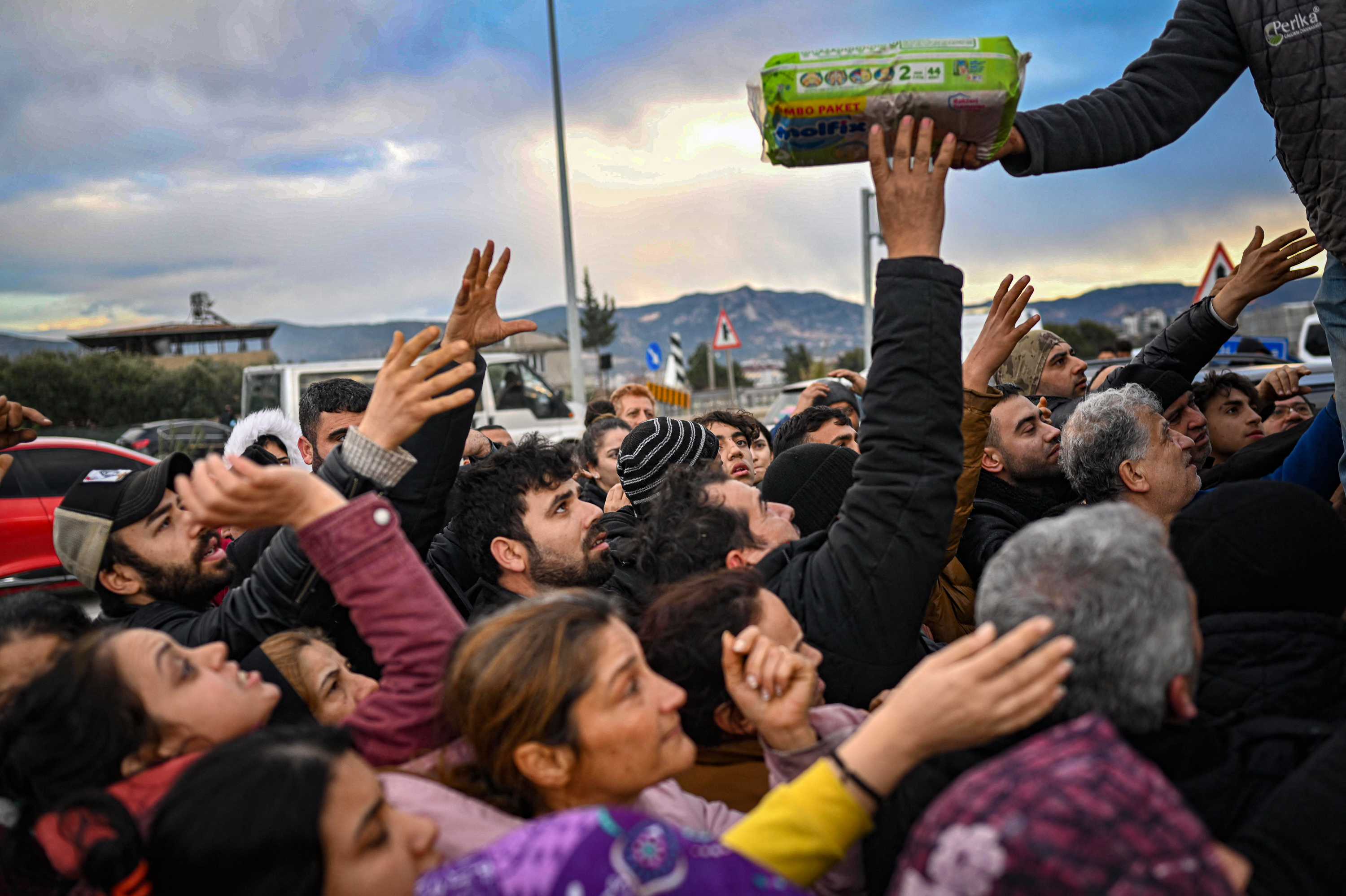 Earthquake survivors gather at a diaper distribution in Hatay, Turkey, on Feb. 7, a day after a 7.8-magnitude earthquake struck the country's southeast. (Bulent Kilic/AFP via Getty Images)