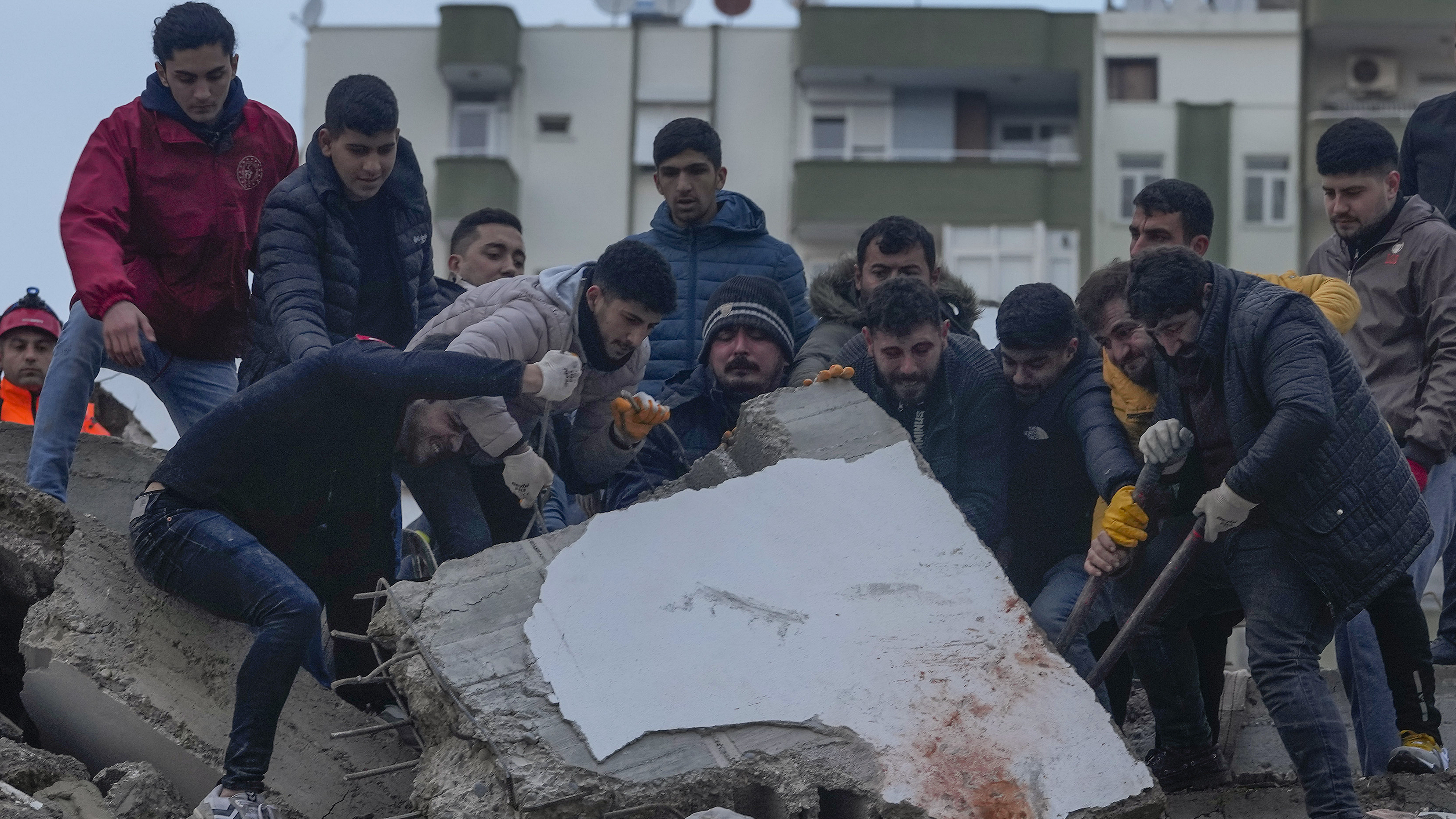 Men search for people among the debris in a destroyed building in Adana, Turkey, Monday.