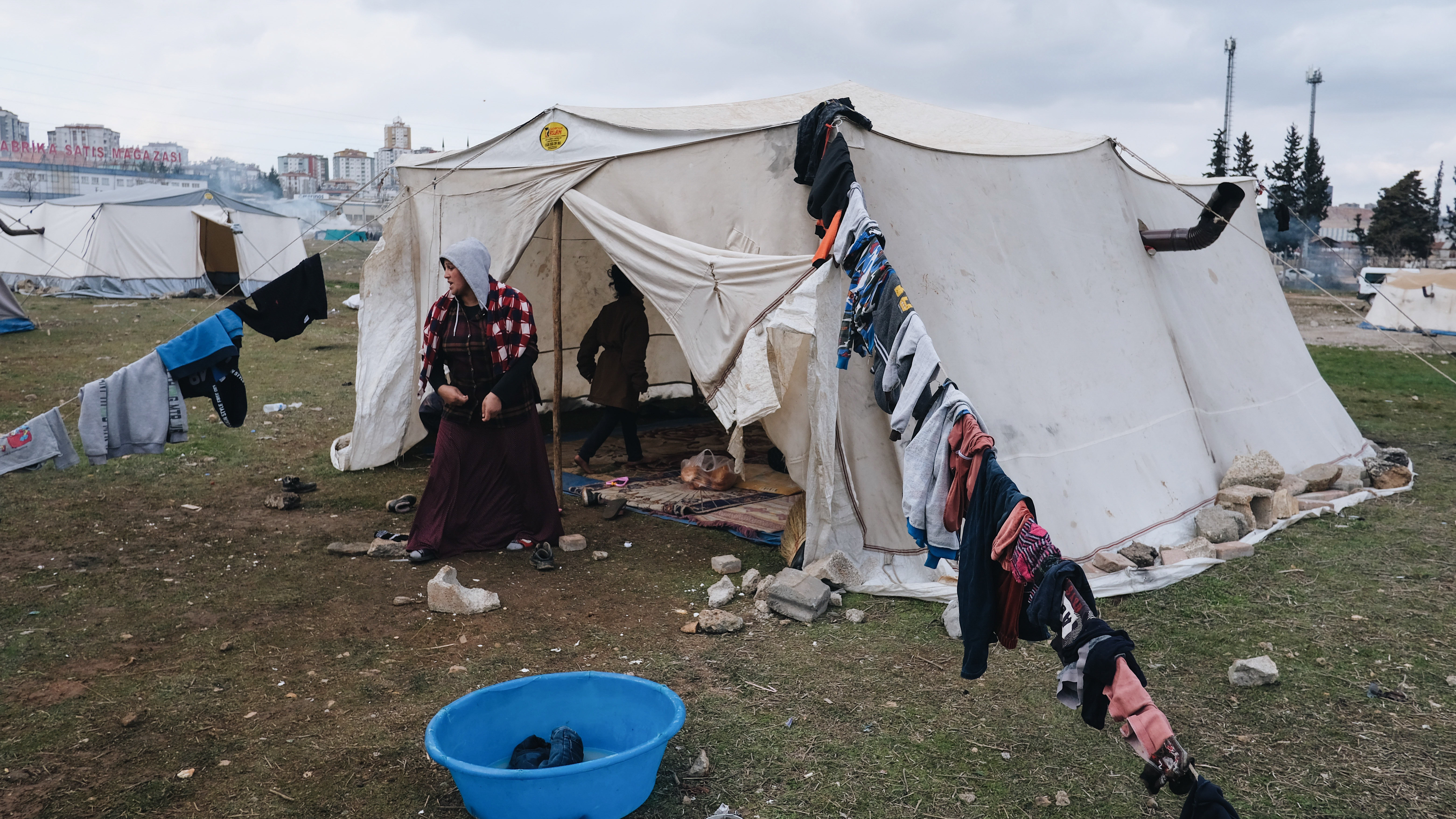 A 26-year-old pregnant woman named Talibe Gezginci cleans her tent in a makeshift camp for displaced people in Gaziantep.