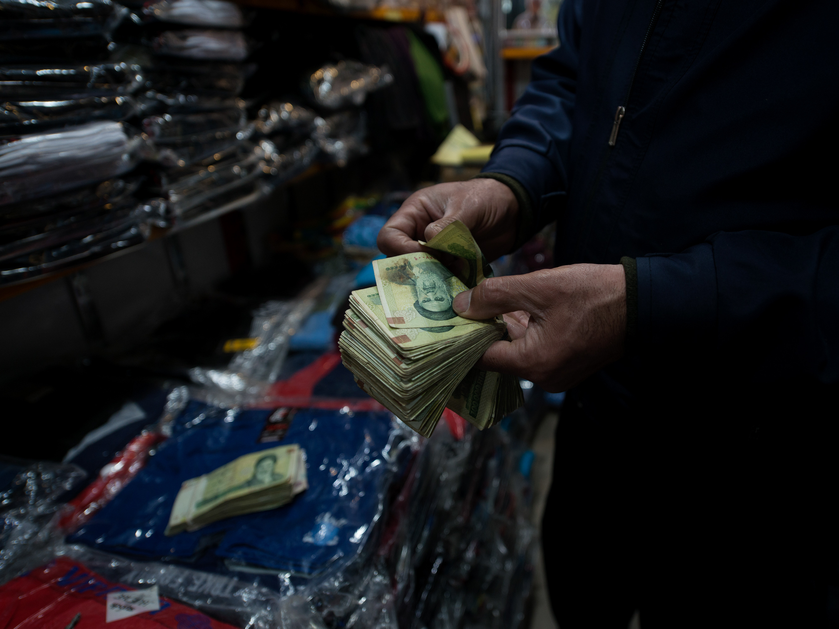 A bazaar shopkeeper counts Iranian bank notes.