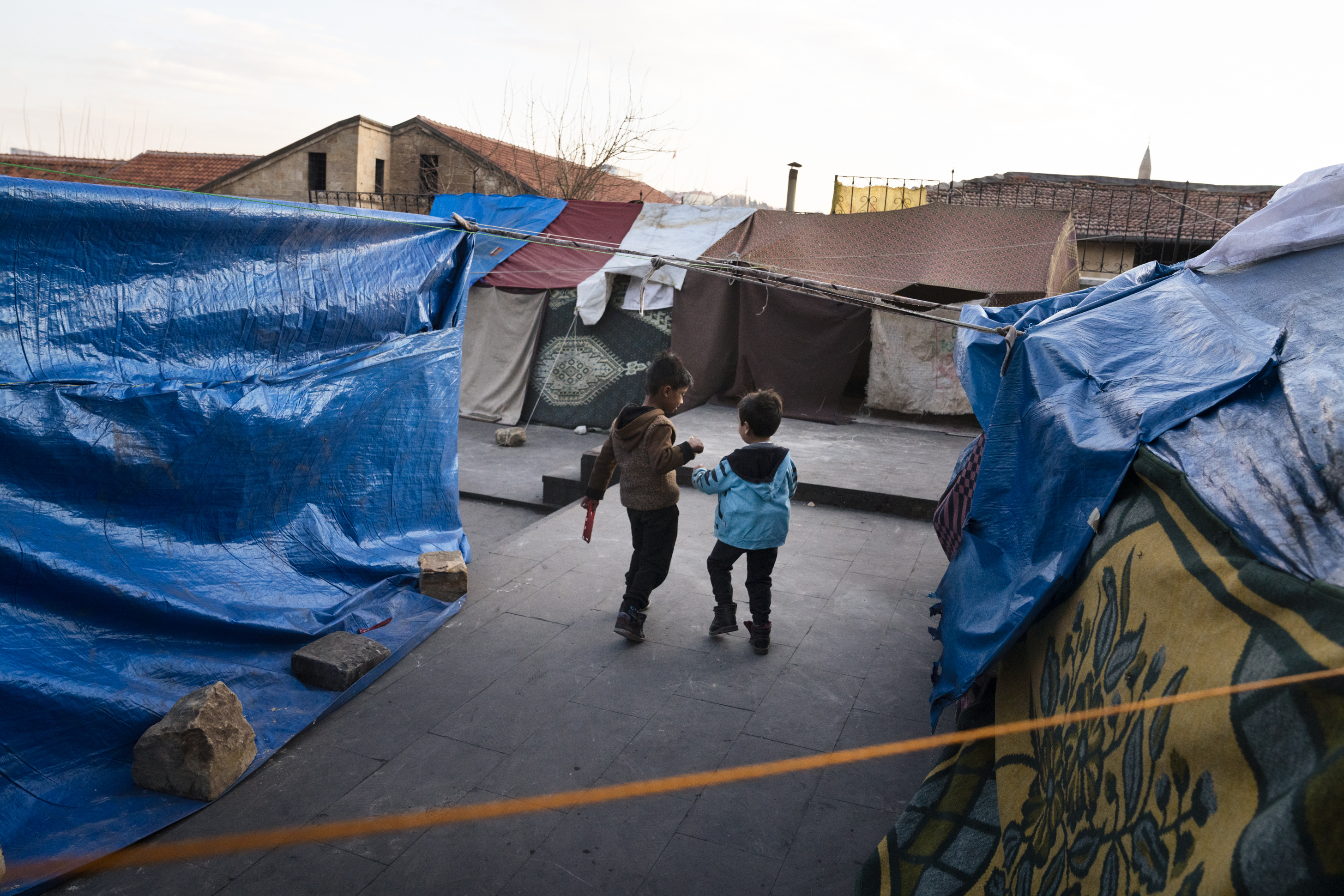 Two boys walk through a small tent encampment in Gaziantep, Turkey, on Thursday, Feb. 16. People have set up makeshift tents since they are too afraid to return to their homes after the earthquake. (NPR)