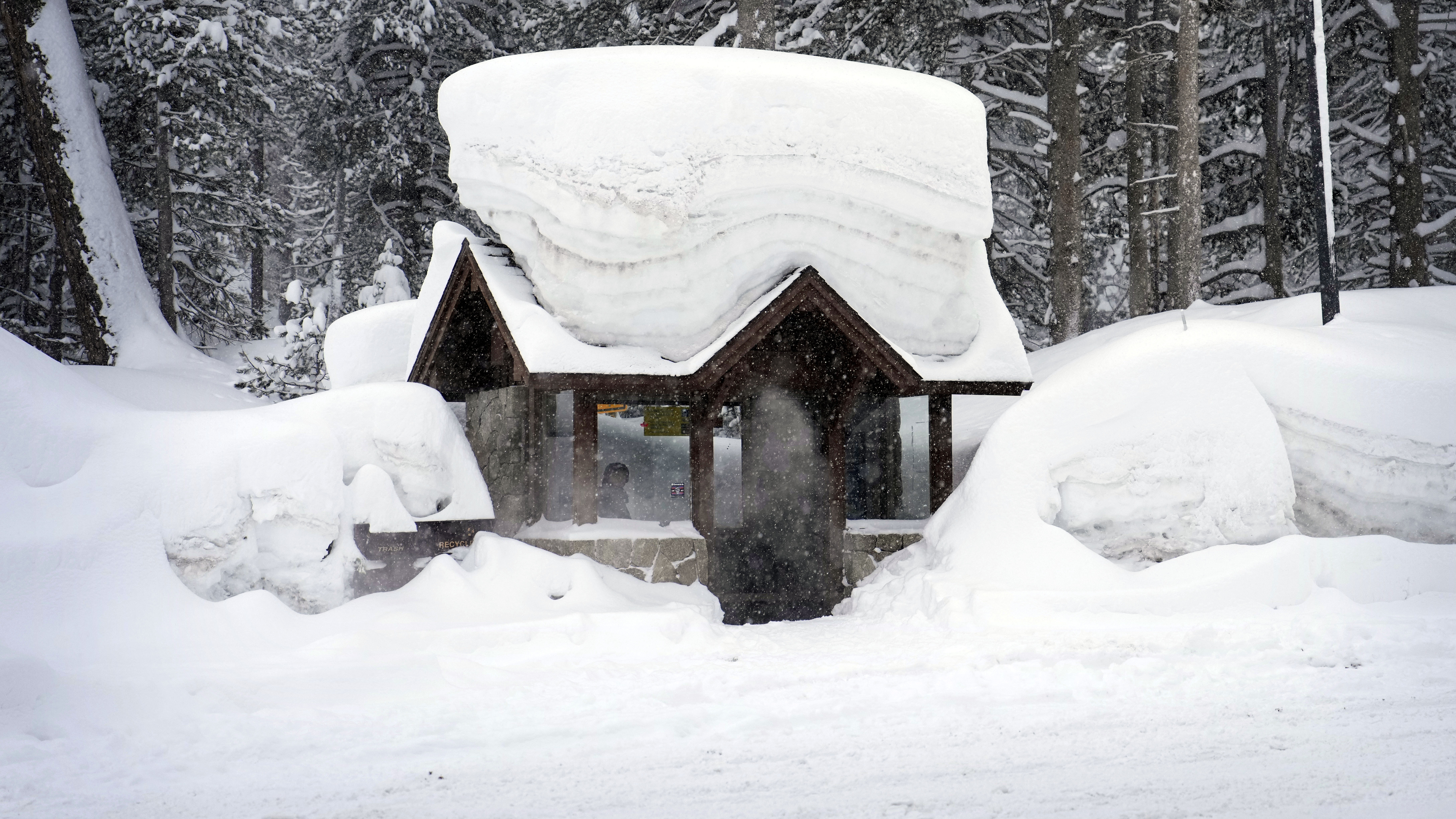 A person sits in a snow-covered bus stop Friday in Olympic Valley, Calif. California and other parts of the West are facing heavy snow and rain from the latest winter storm to pound the United States.