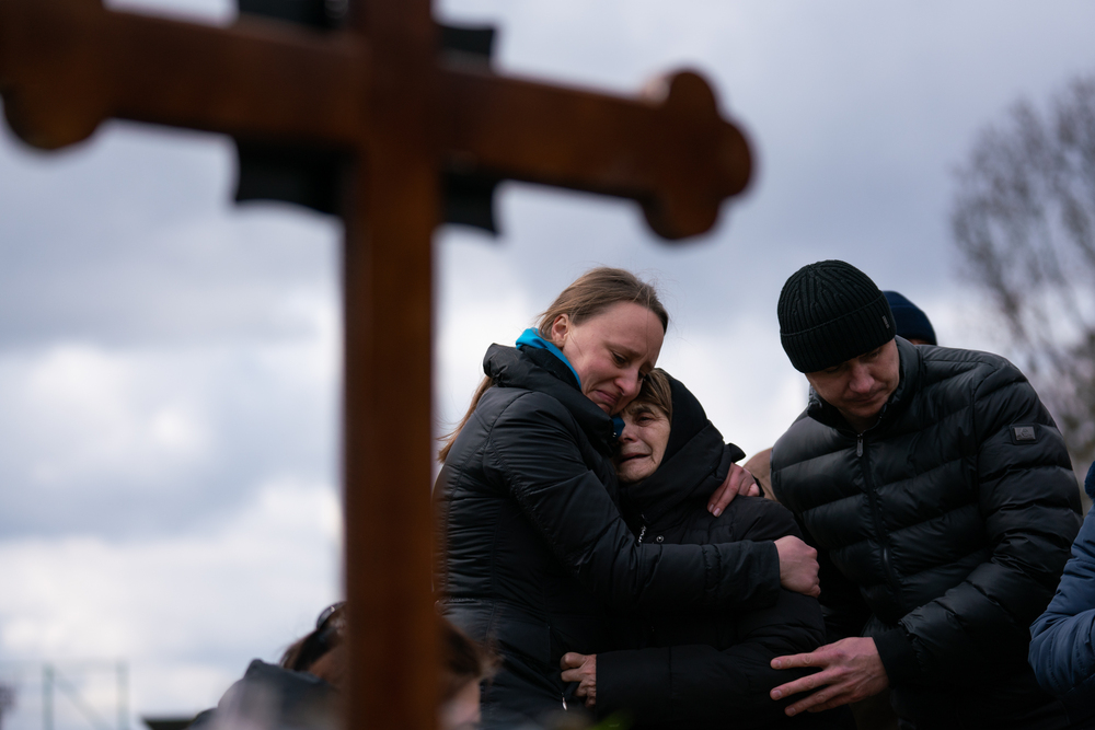 Ukrainian journalist-turned-soldier Viktor Dudar's mother (center) grieves at his grave as he's laid to rest in Lviv, Ukraine, last March. Last week the world marked the first anniversary of Russia's large-scale invasion of Ukraine. (NPR)