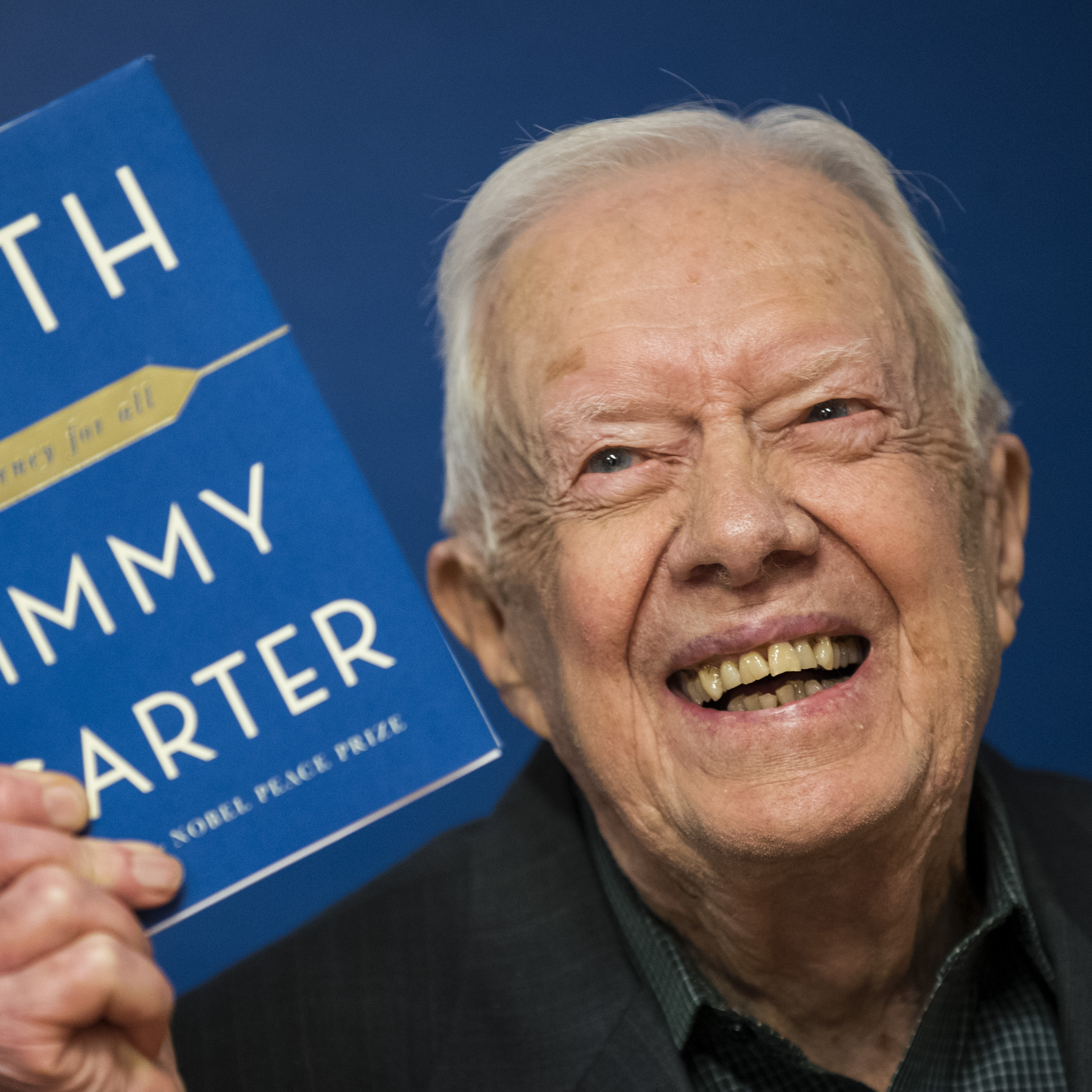 Former U.S. President Jimmy Carter holds up a copy of his book Faith: A Journey For All at a book signing event at Barnes & Noble bookstore on March 26, 2018.