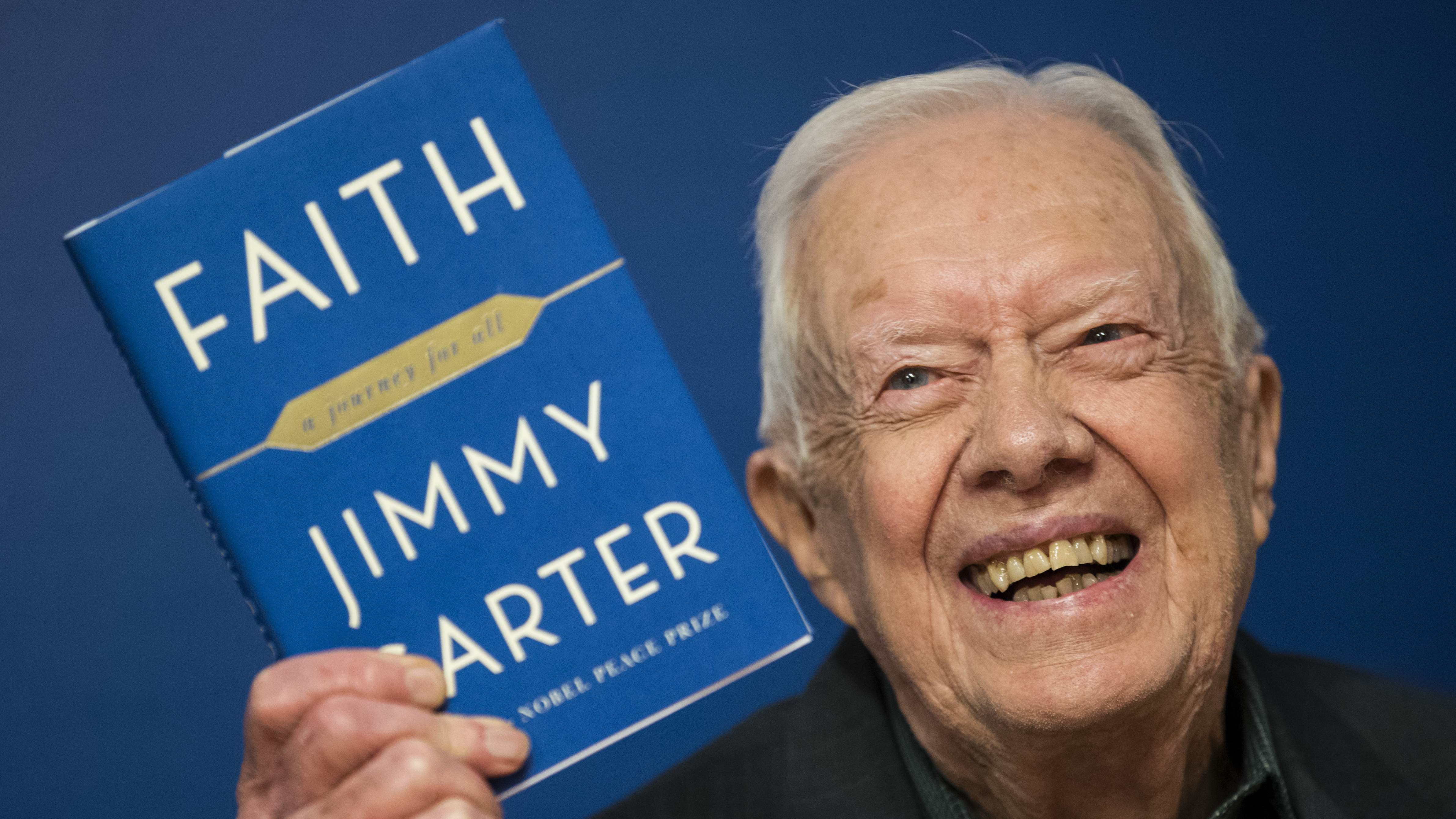 Former U.S. President Jimmy Carter holds up a copy of his book Faith: A Journey For All at a book signing event at Barnes & Noble bookstore on March 26, 2018.