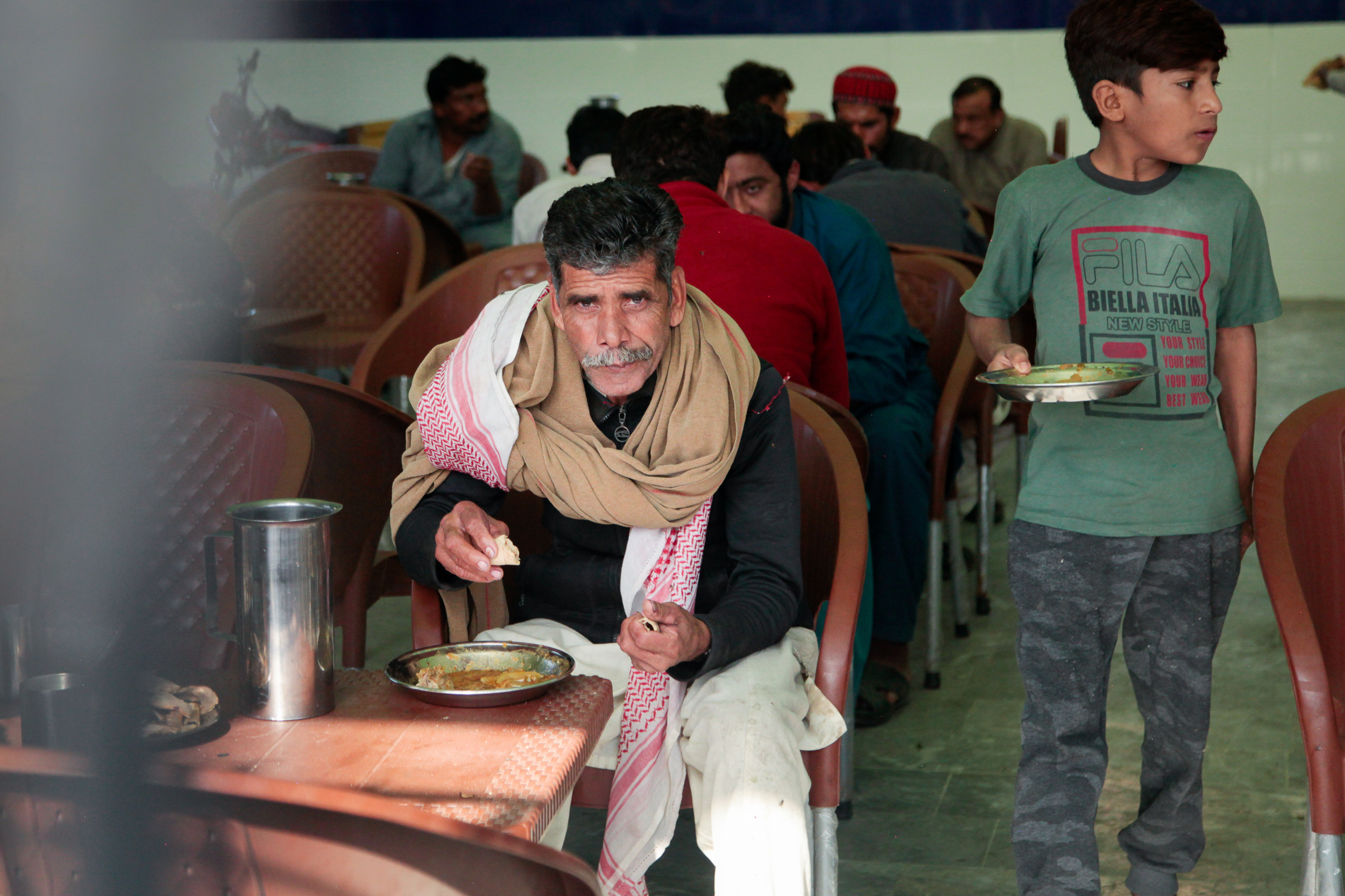 Men eat at a free cafeteria operated by the Pakistani charity Saylani. This cafeteria was recently opened to serve workers in the textile mills on the outskirts of the city of Faisalabad. It's one of 40 cafeterias the charity runs in Faislabad – nearly double what they operated two years ago, as the number of hungry grow.