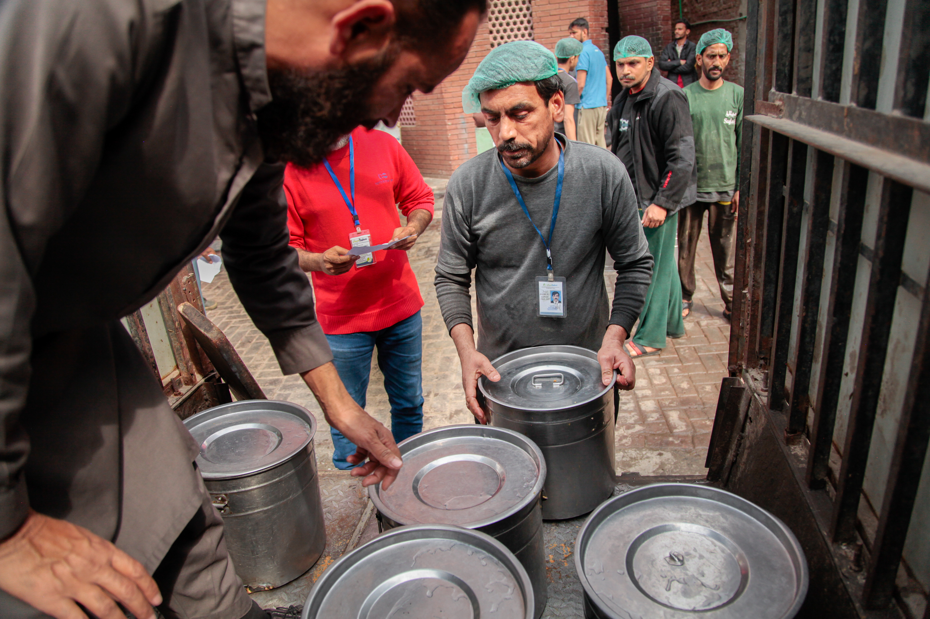 A worker at the Pakistani charity Saylani supervises the loading of vats of freshly cooked food into an open-backed jeep. The food will be distributed to 40 free cafeterias run by the charity in the city of Faisalabad.