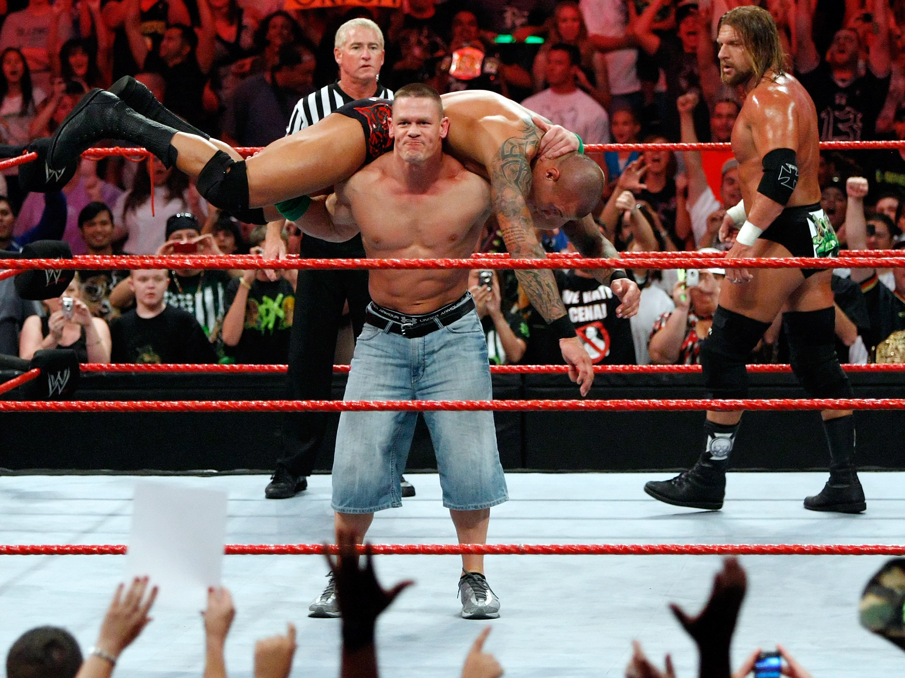 LAS VEGAS - Wrestler John Cena picks up wrestler Randy Orton as wrestler Triple H (R) looks on during the WWE Monday Night Raw show at the Thomas & Mack Center August 24, 2009 in Las Vegas, Nevada. (Getty Images)
