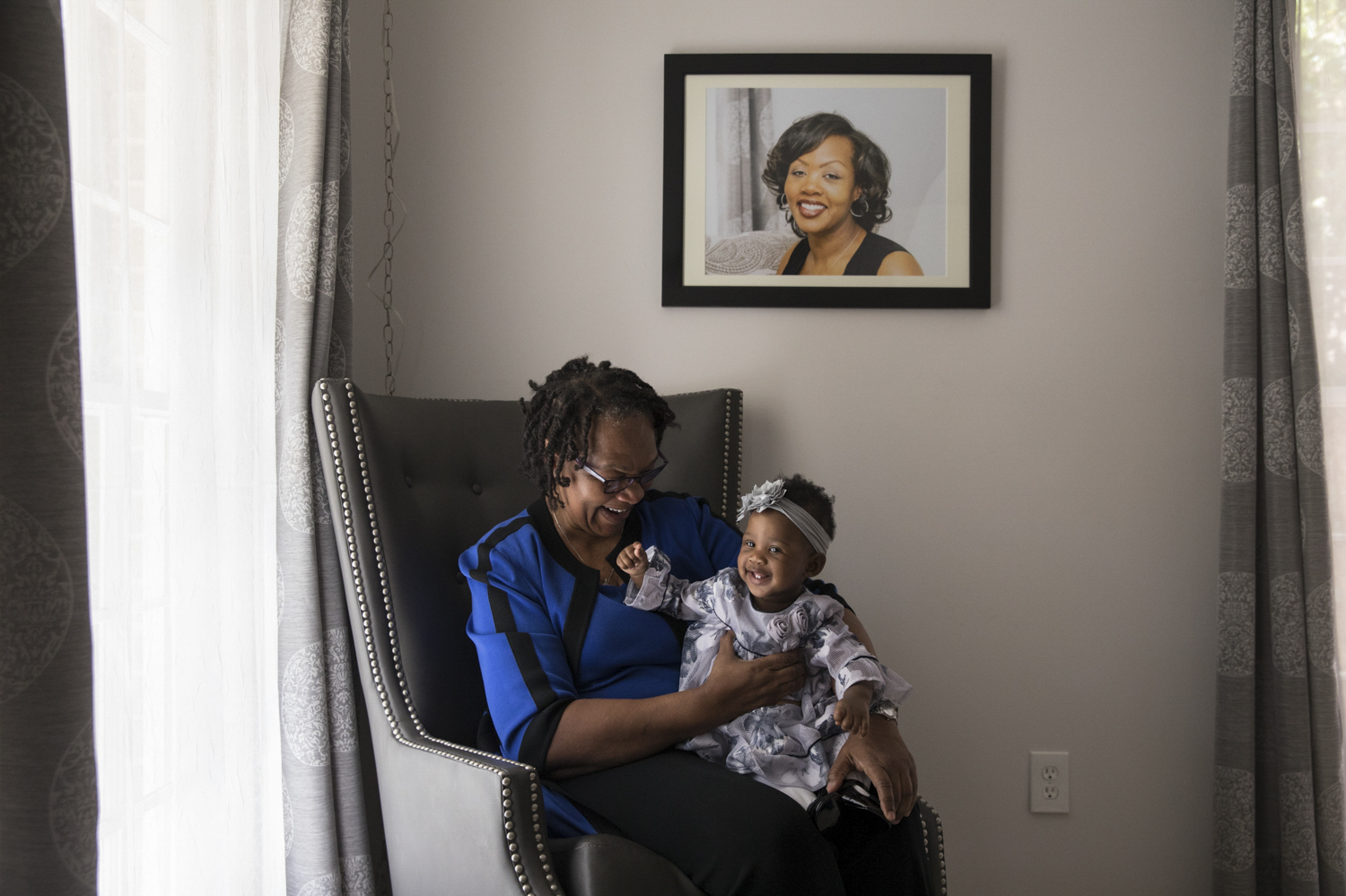 Wanda Irving holds her granddaughter, Soleil, in front of a portrait of Soleil's mother, Shalon Irving, at her home in Sandy Springs, Ga., in 2017. Wanda is raising Soleil since Shalon died of complications due to hypertension a few weeks after giving birth. (NPR)