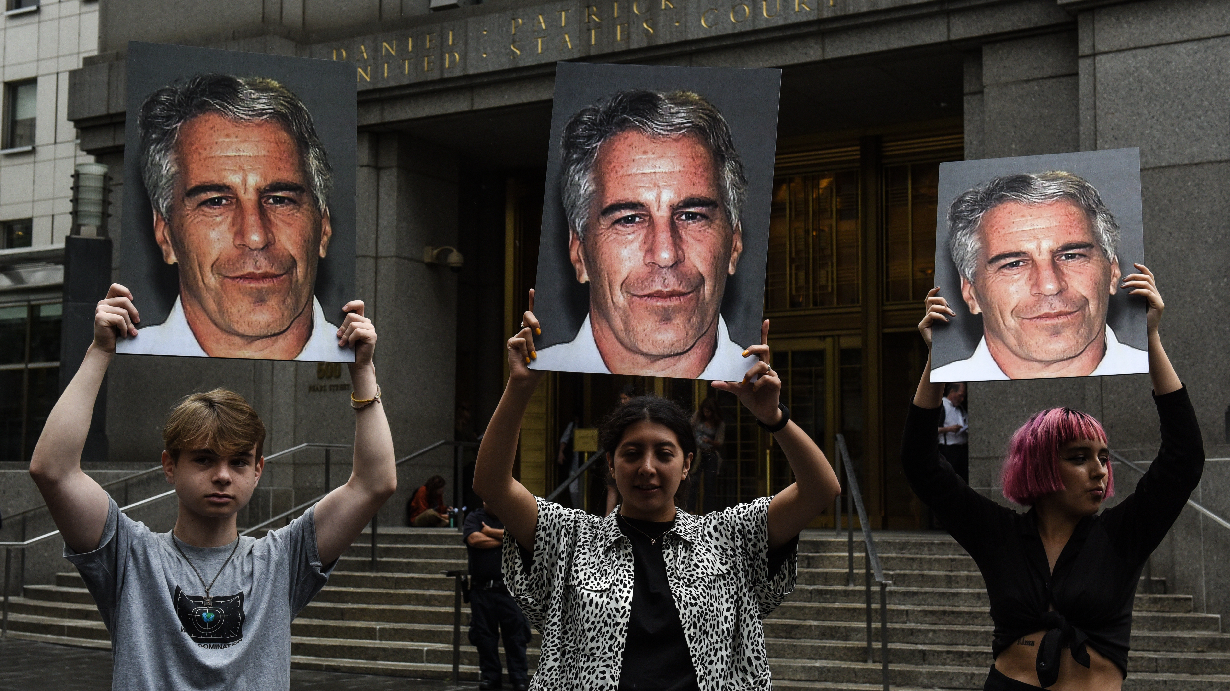 A group of protesters hold photos of Jeffrey Epstein in front of a New York City federal courthouse in July 2019. A Southern District judge ruled this week that three lawsuits against banks that Epstein used can move forward.