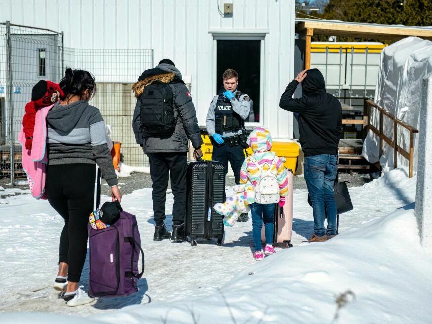 An officer speaks to migrants as they arrive at the Roxham Road border crossing in Quebec, Canada, earlier this month. (AFP via Getty Images)