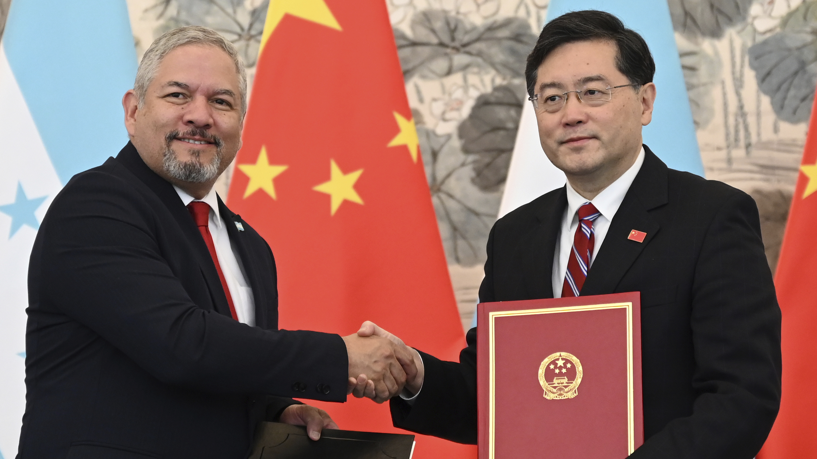 Honduras Foreign Minister Eduardo Enrique Reina Garcia, left, and Chinese Foreign Minister Qin Gang shake hands following the establishment of diplomatic relations between the two countries, at a ceremony in the Diaoyutai State Guesthouse in Beijing Sunday, March 26, 2023.