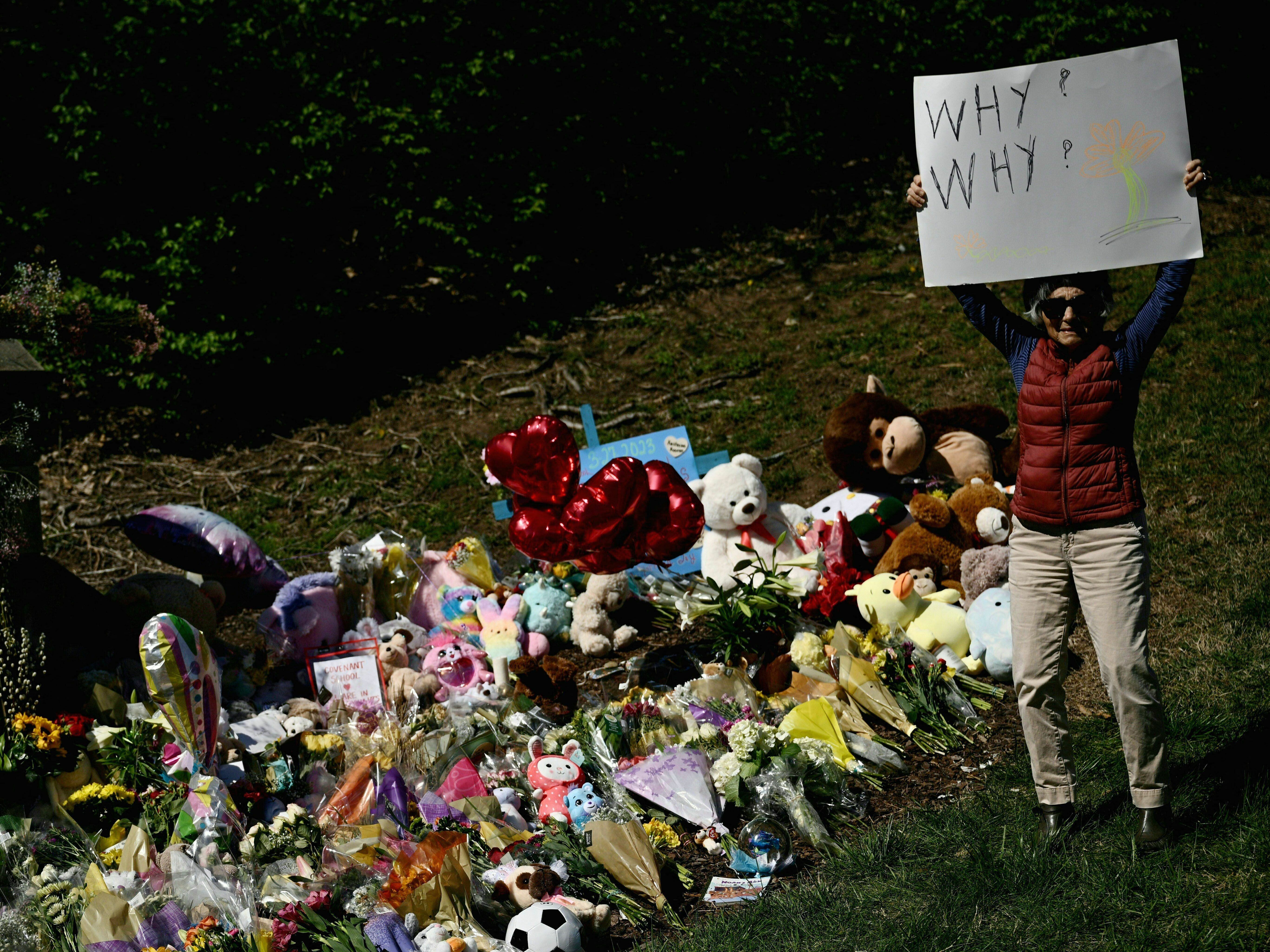 A mourner on Wednesday holds a sign reading &quot;Why? Why?&quot; at a makeshift memorial for victims of the shooting at the Covenant School in Nashville, Tennessee. (AFP via Getty Images)