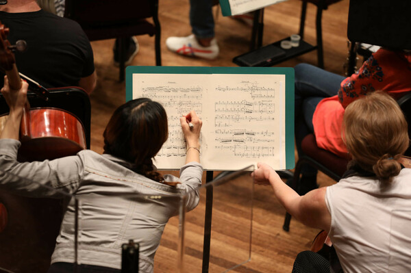 Musicians take notes during the rehearsal.