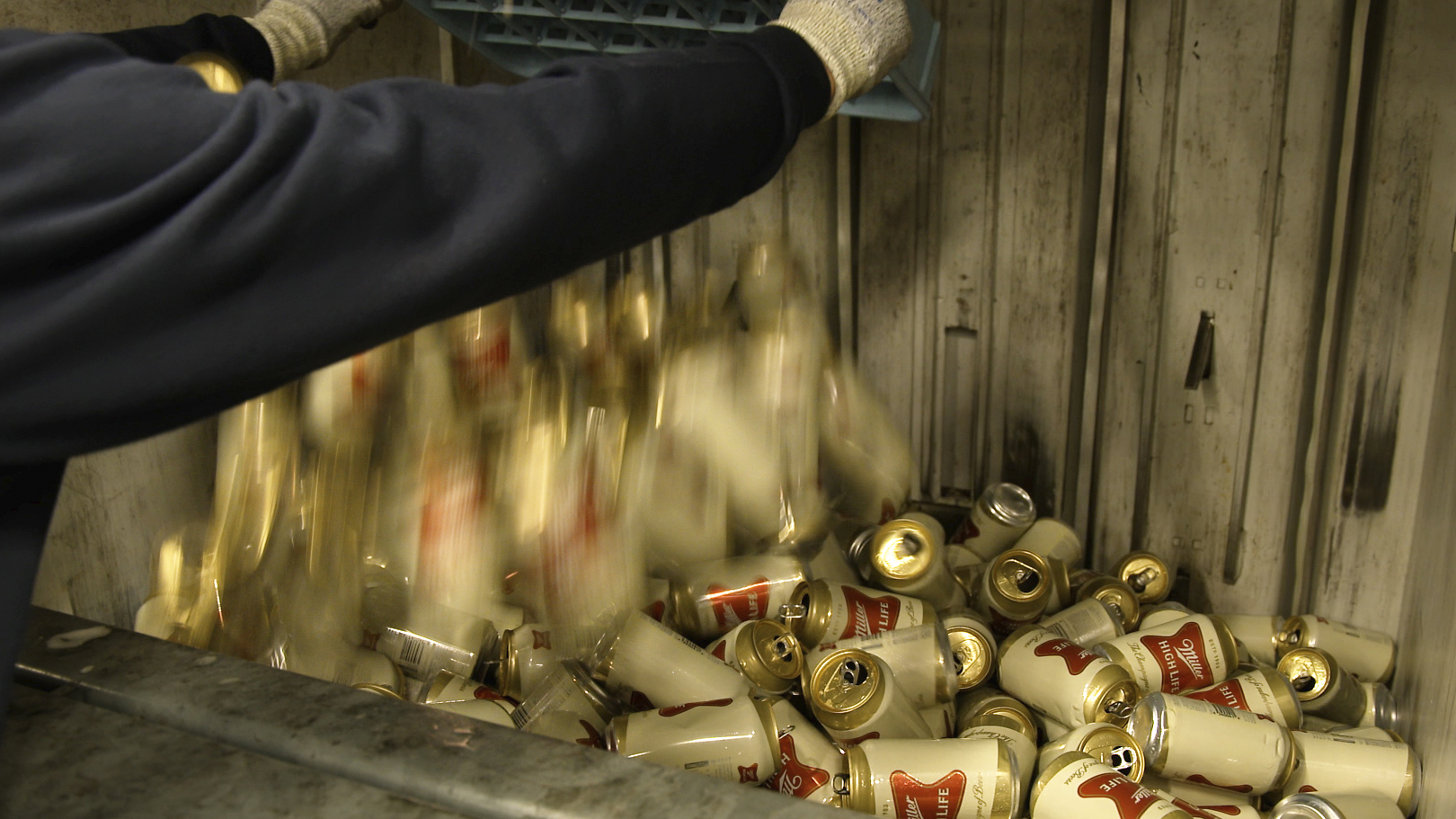 A worker dumps empty cans of Miller High Life beer into a machine to be crushed at the Westlandia plant in Ypres, Belgium, on Monday.